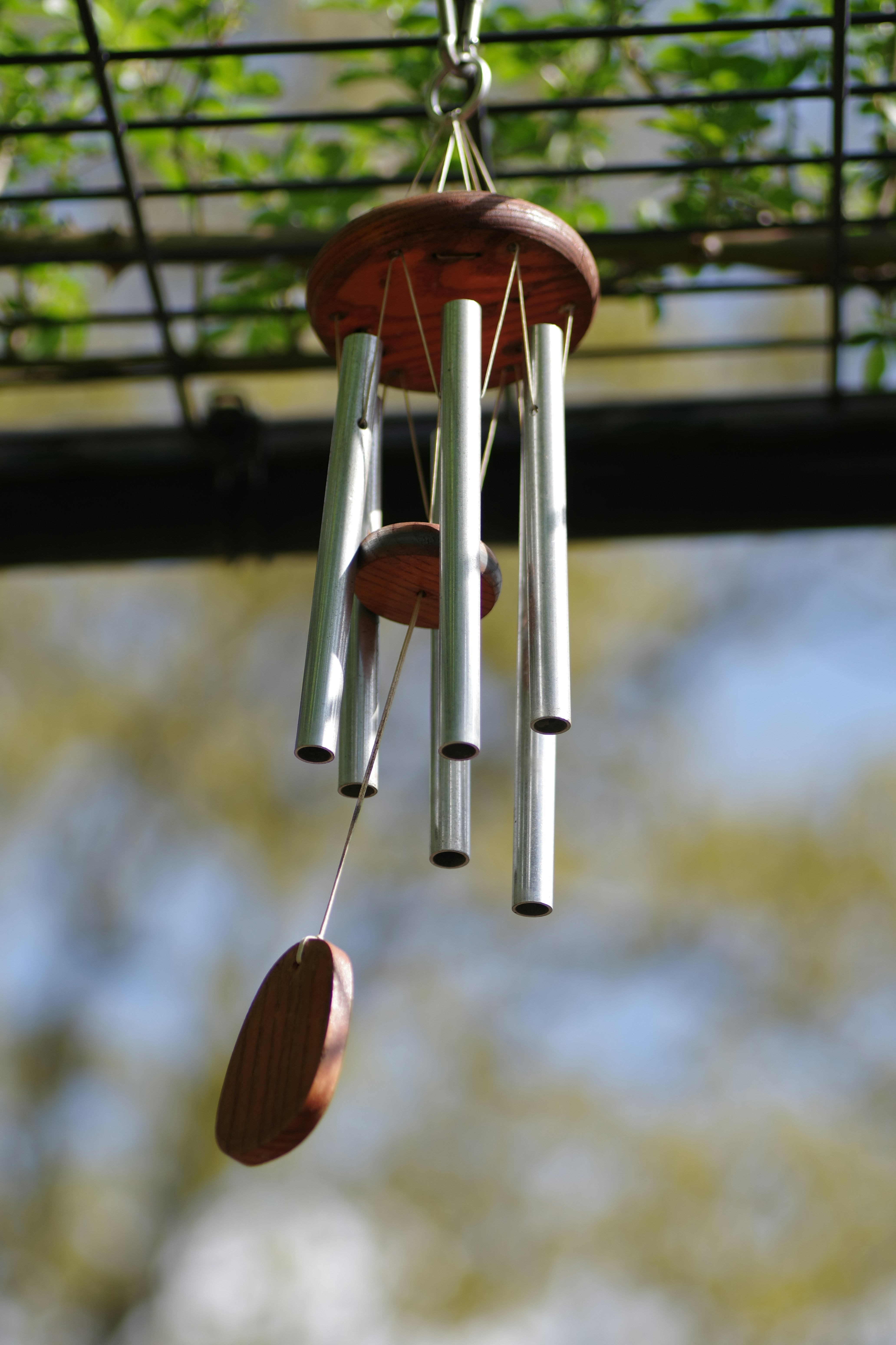 Wind chimes hang outside on a sunny day.
