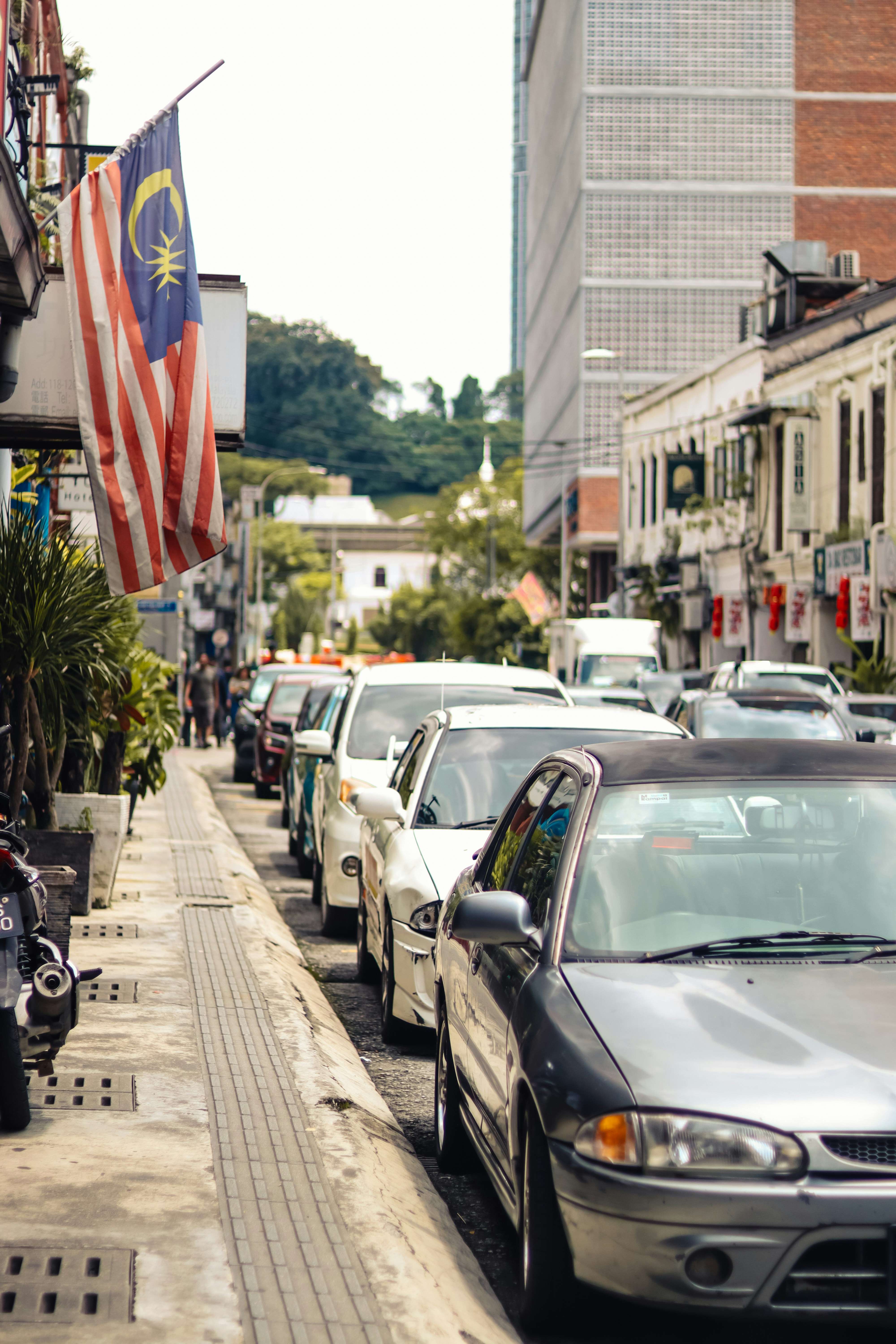Des voitures bordent une rue avec le drapeau malaisien.