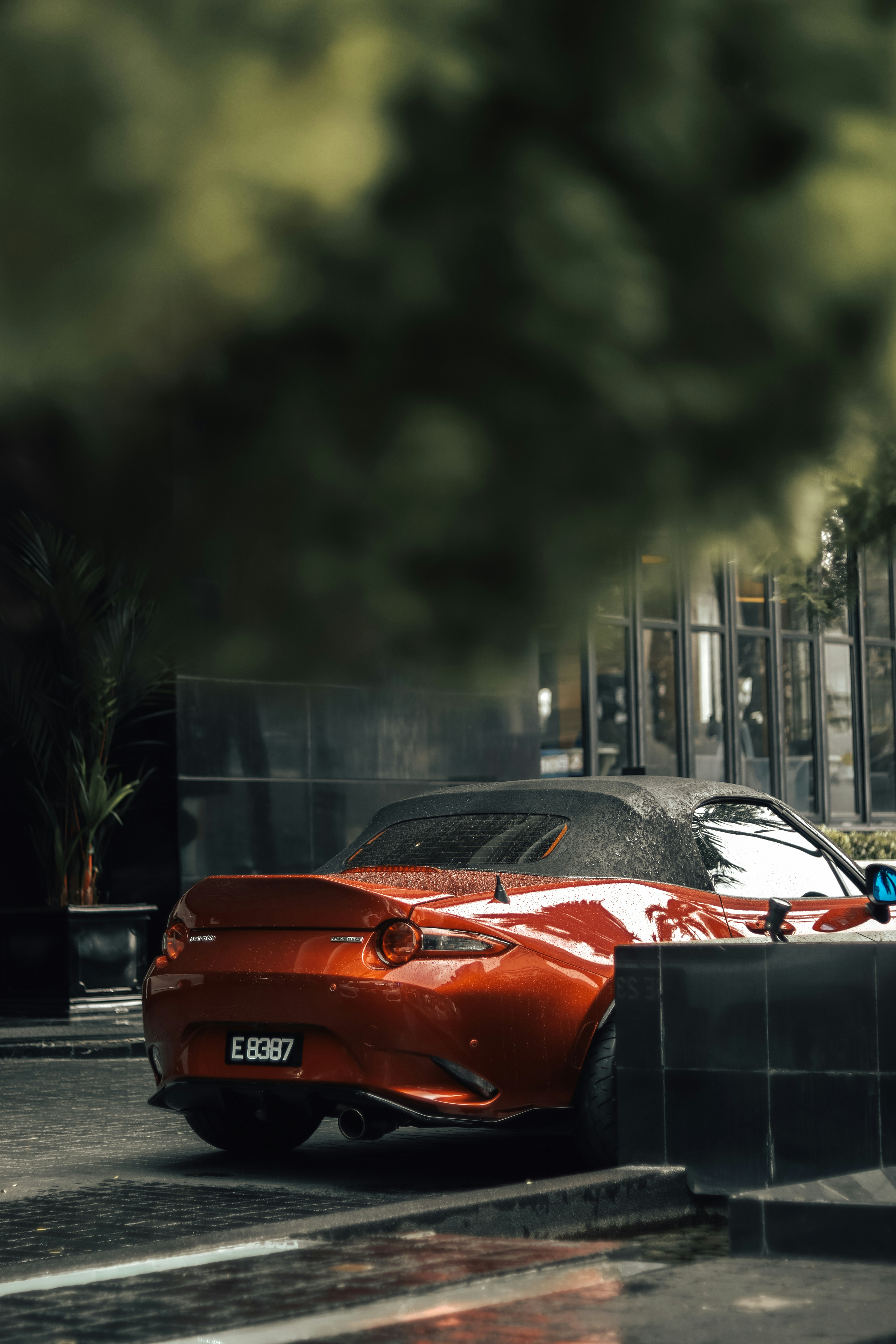 Une cabriolet rouge est garée près d’un immeuble.