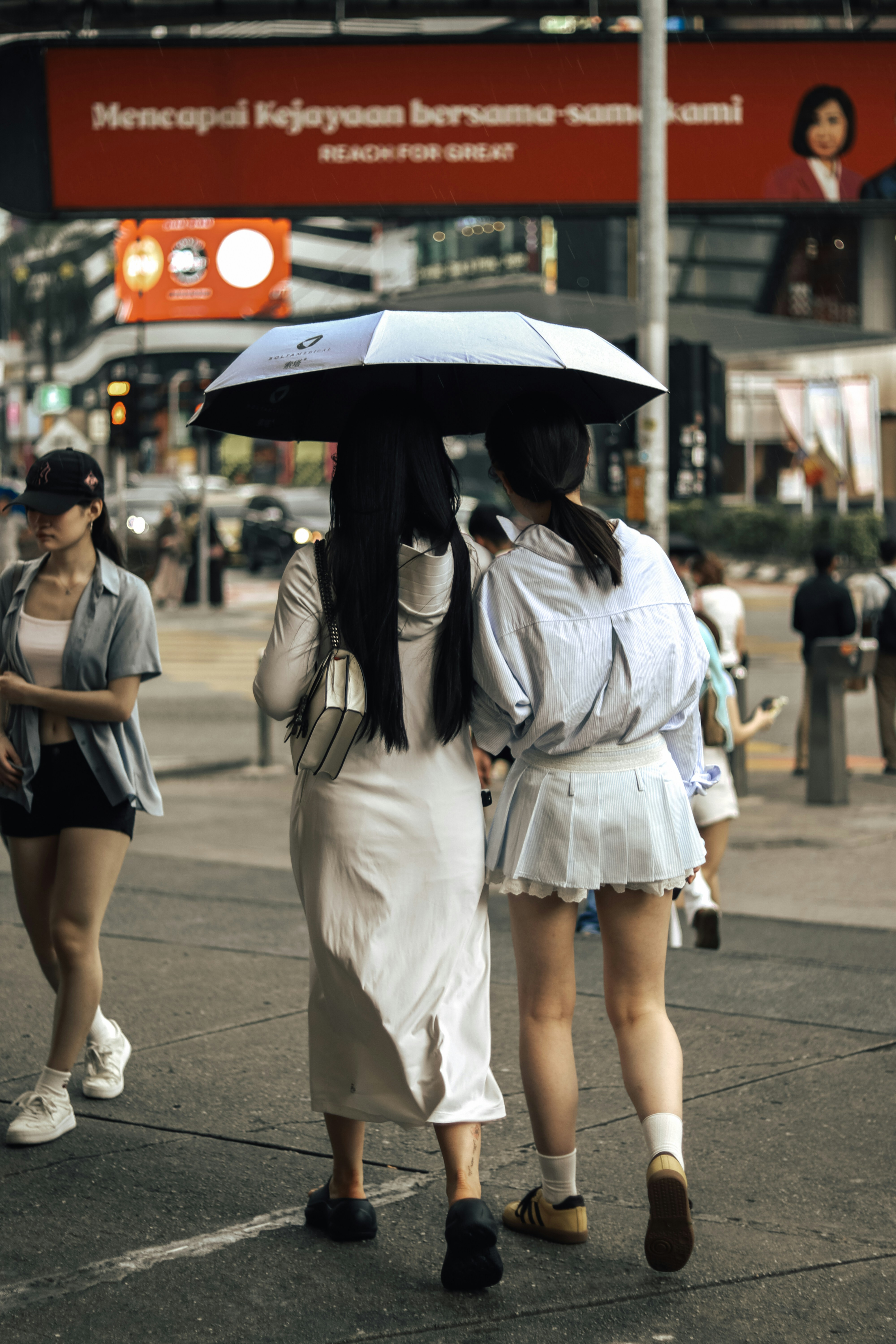 Deux femmes marchent ensemble avec un parapluie.