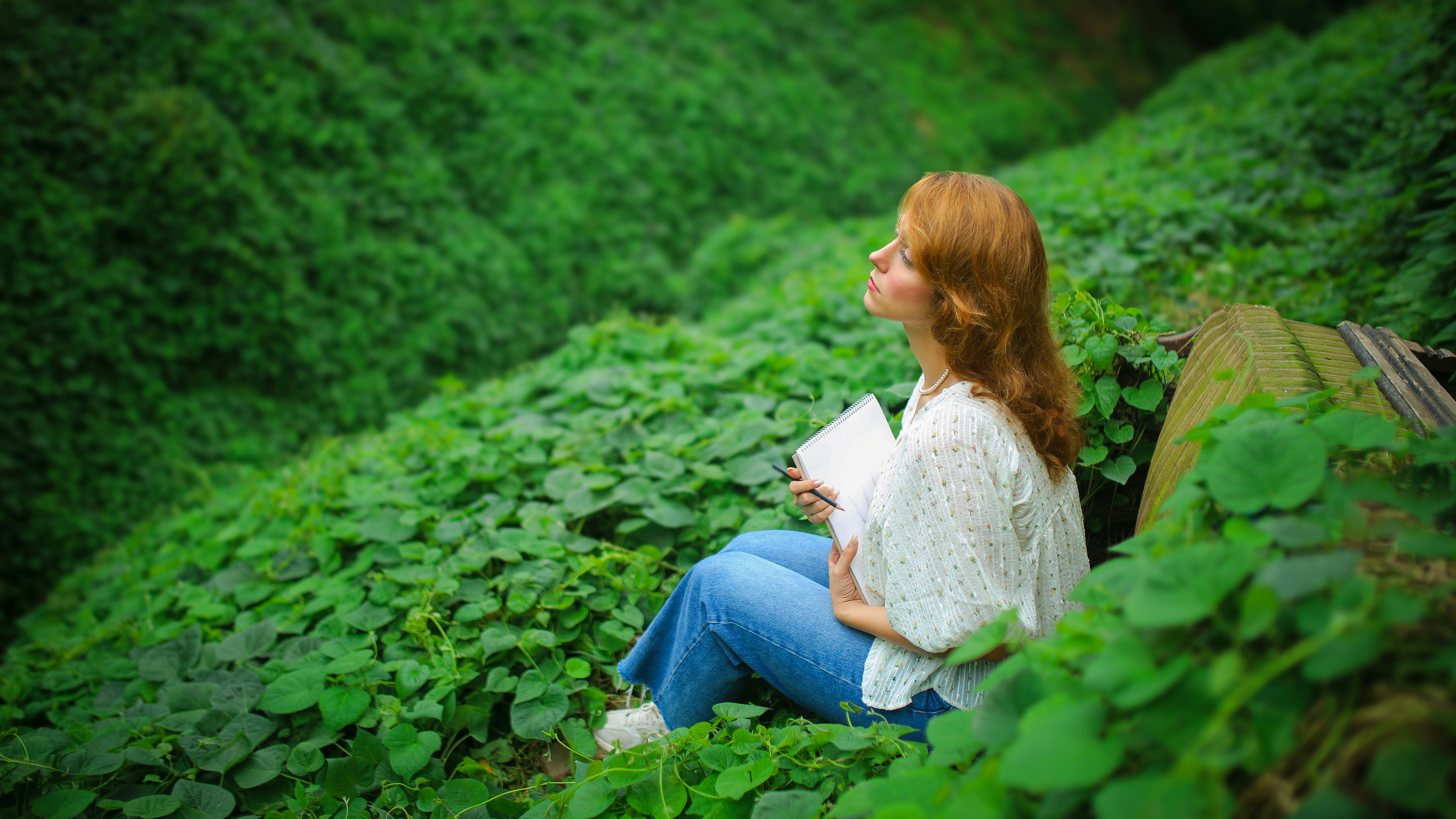 豊かな緑の中で本を読む女性。
