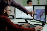 Colleagues collaborate while examining computer designs.