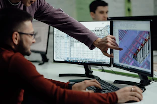 Colleagues collaborate while examining computer designs.