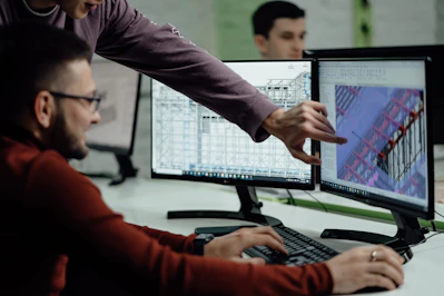 Colleagues collaborate while examining computer designs.