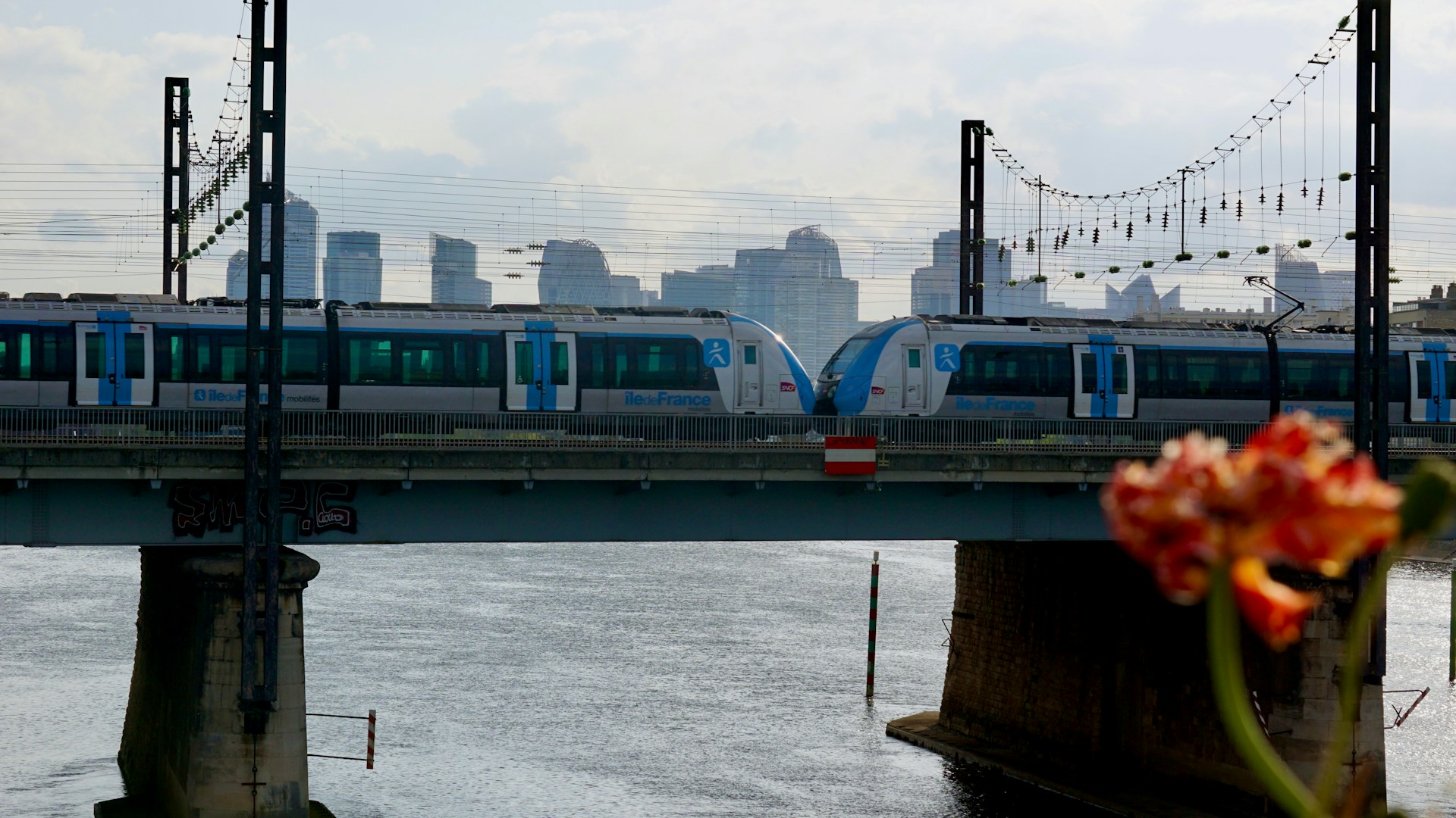 Trains are crossing a bridge with a city skyline.