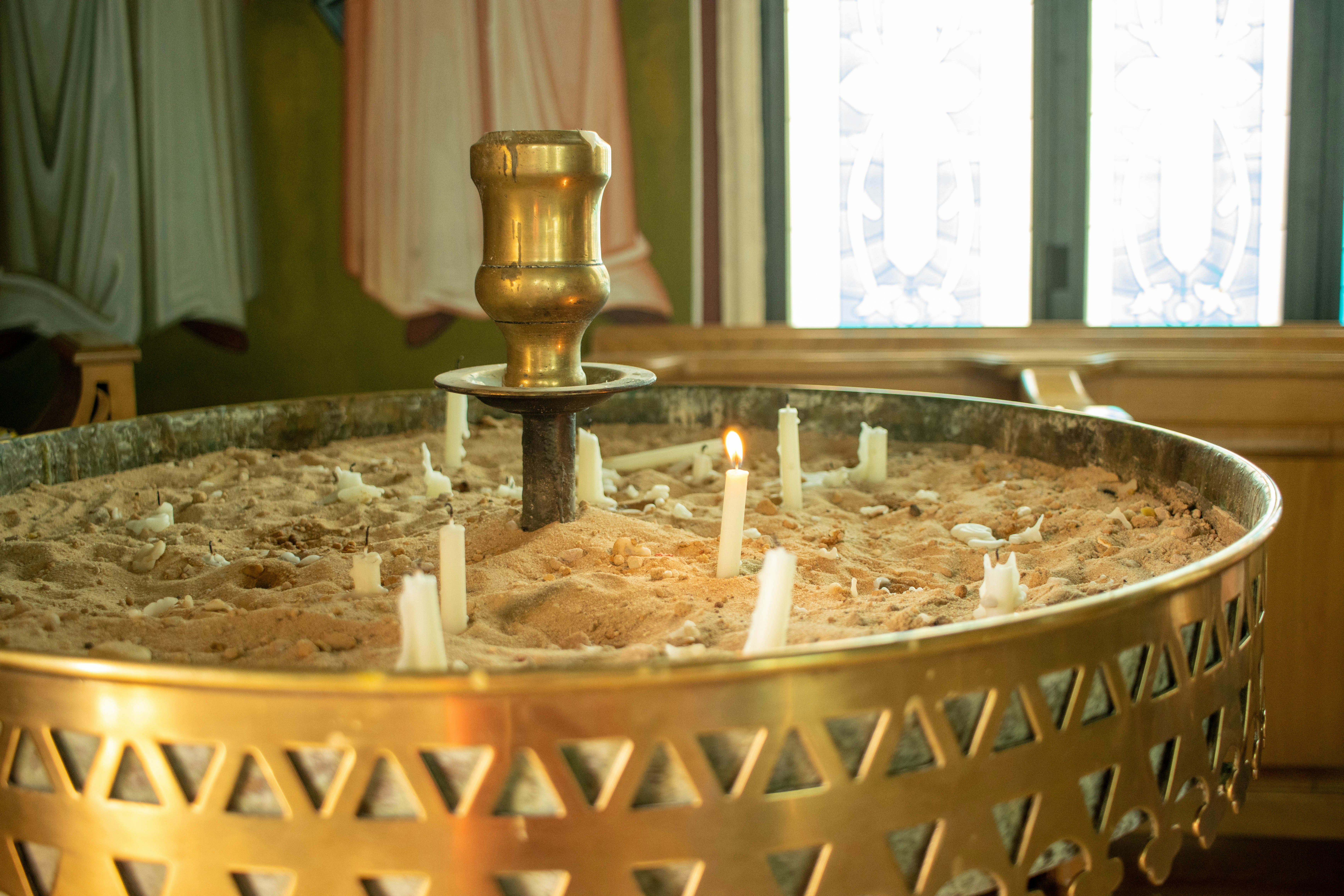 Candles are lit in a golden container