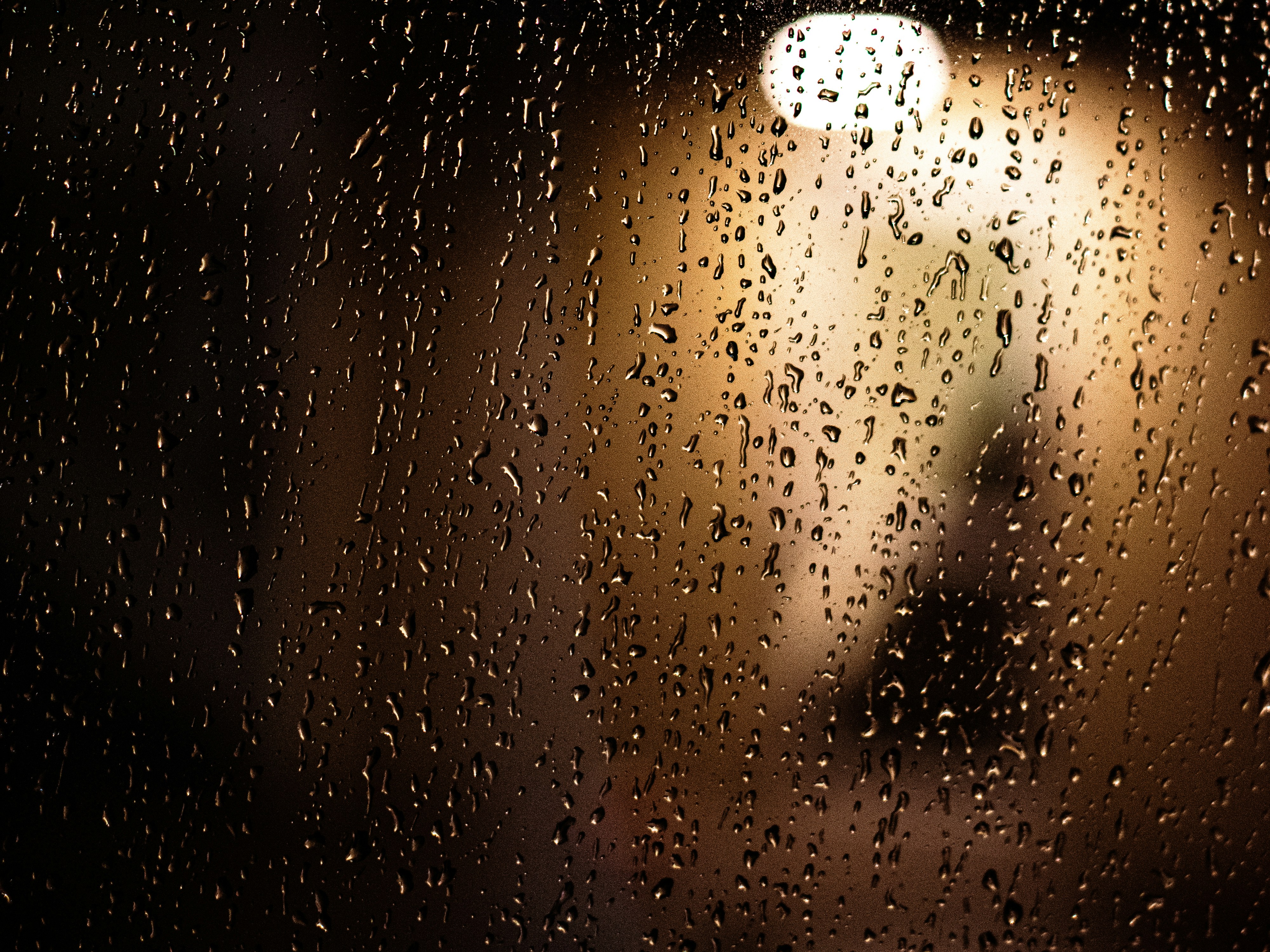 Regentropfen auf Glas mit verschwommenem Licht.