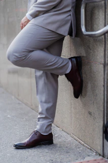 A man in a suit leans against a wall.