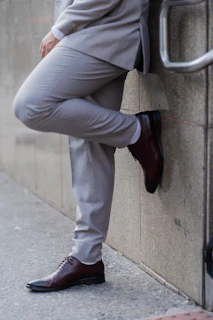 A man in a suit leans against a wall.
