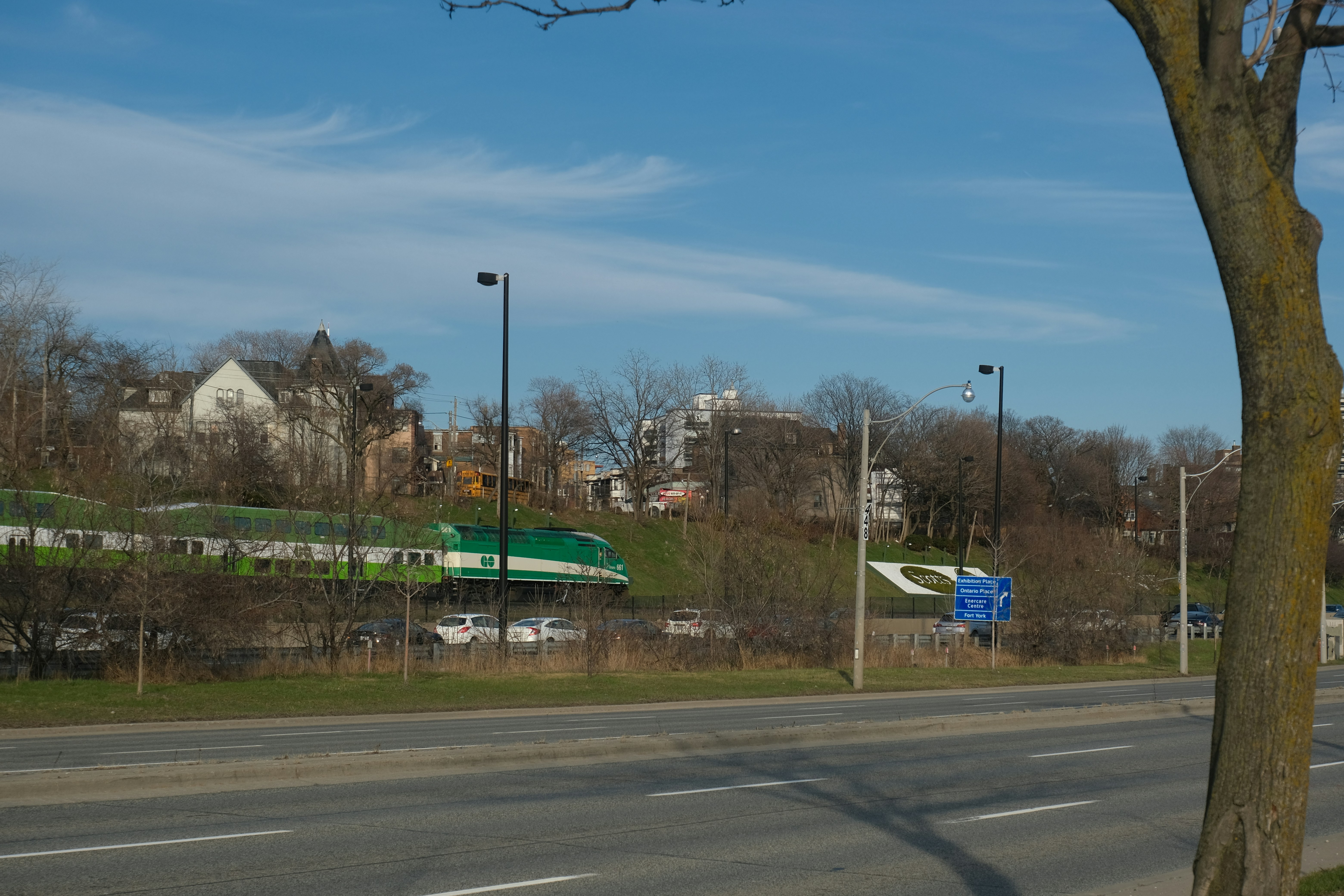 Un tren verde pasa por delante de casas residenciales.