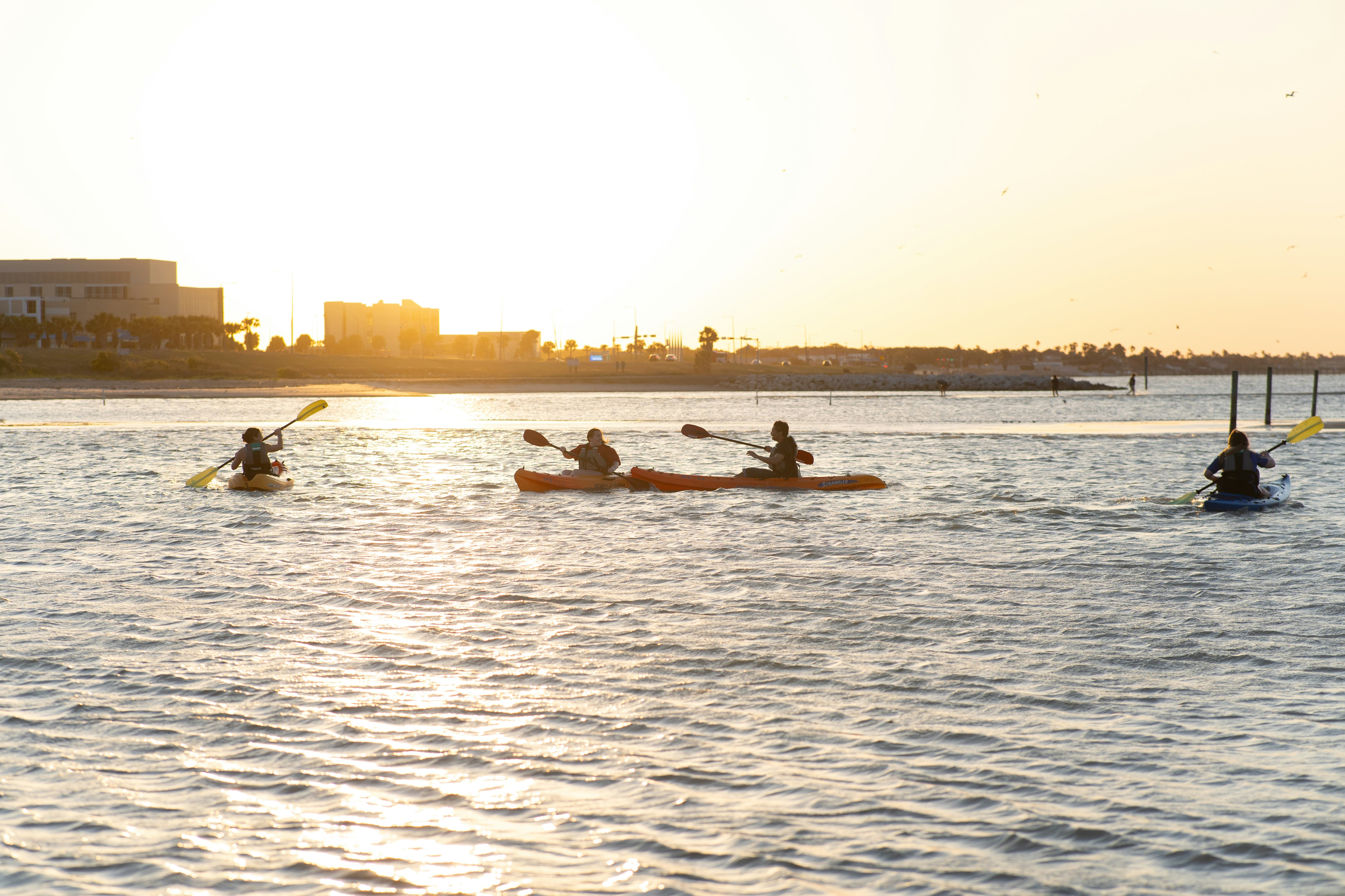 Kayakers enjoy a sunset paddle on the water.