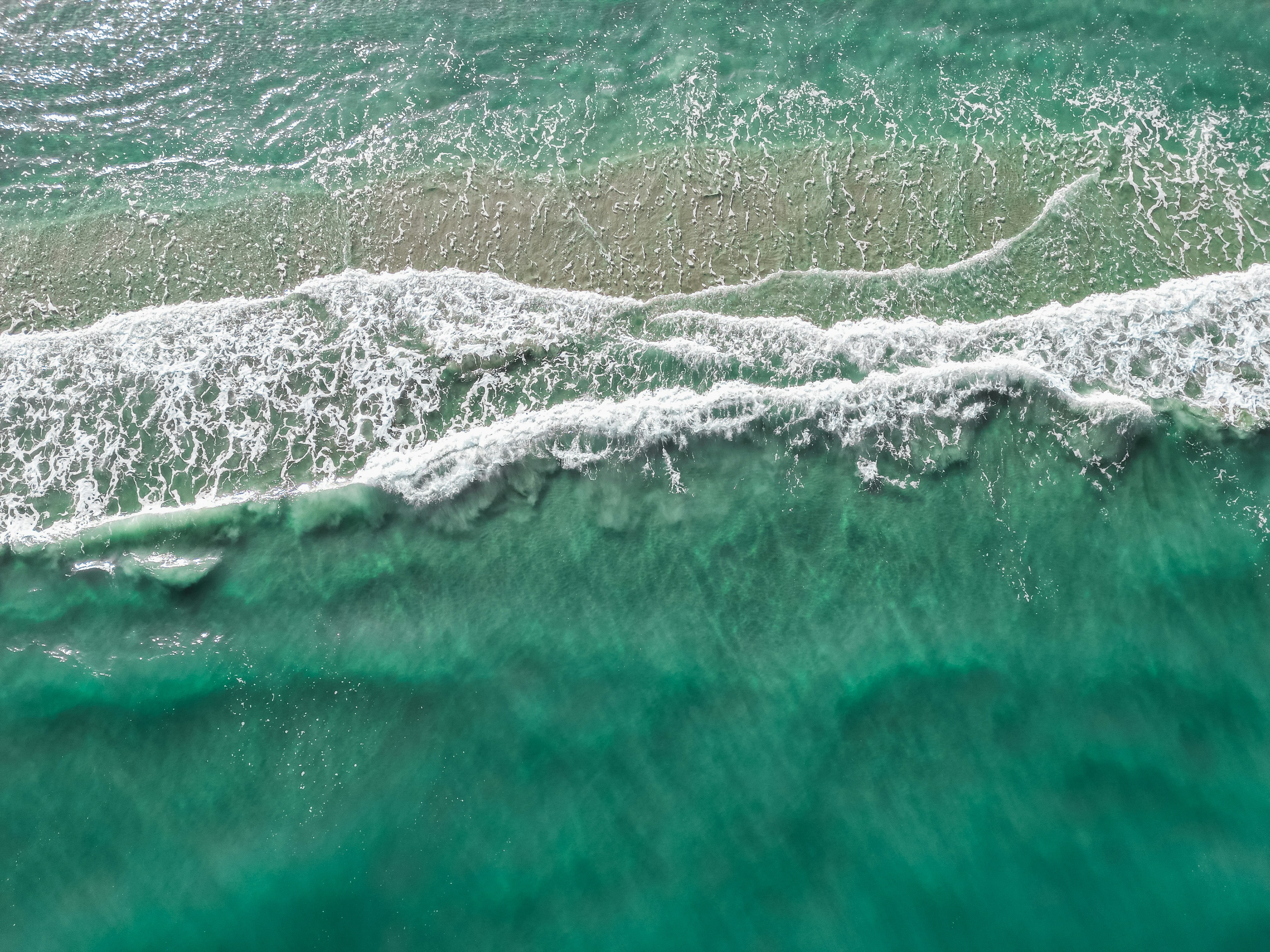 Here's a caption: ocean waves crash on the sandy shore.
