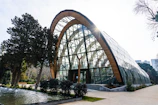 A modern glass building with a wooden arch.