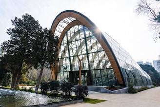 A modern glass building with a wooden arch.