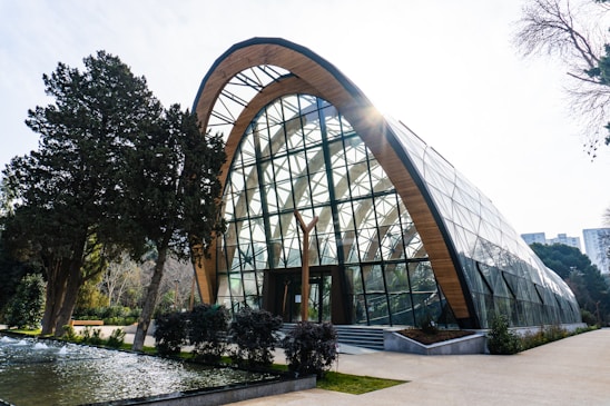 A modern glass building with a wooden arch.