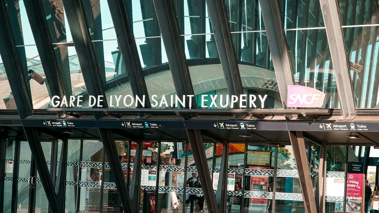 Façade vitrée de la gare de Lyon Saint-Exupéry avec son nom et le logo SNCF au-dessus des entrées