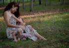 A mother breastfeeds her baby outdoors.
