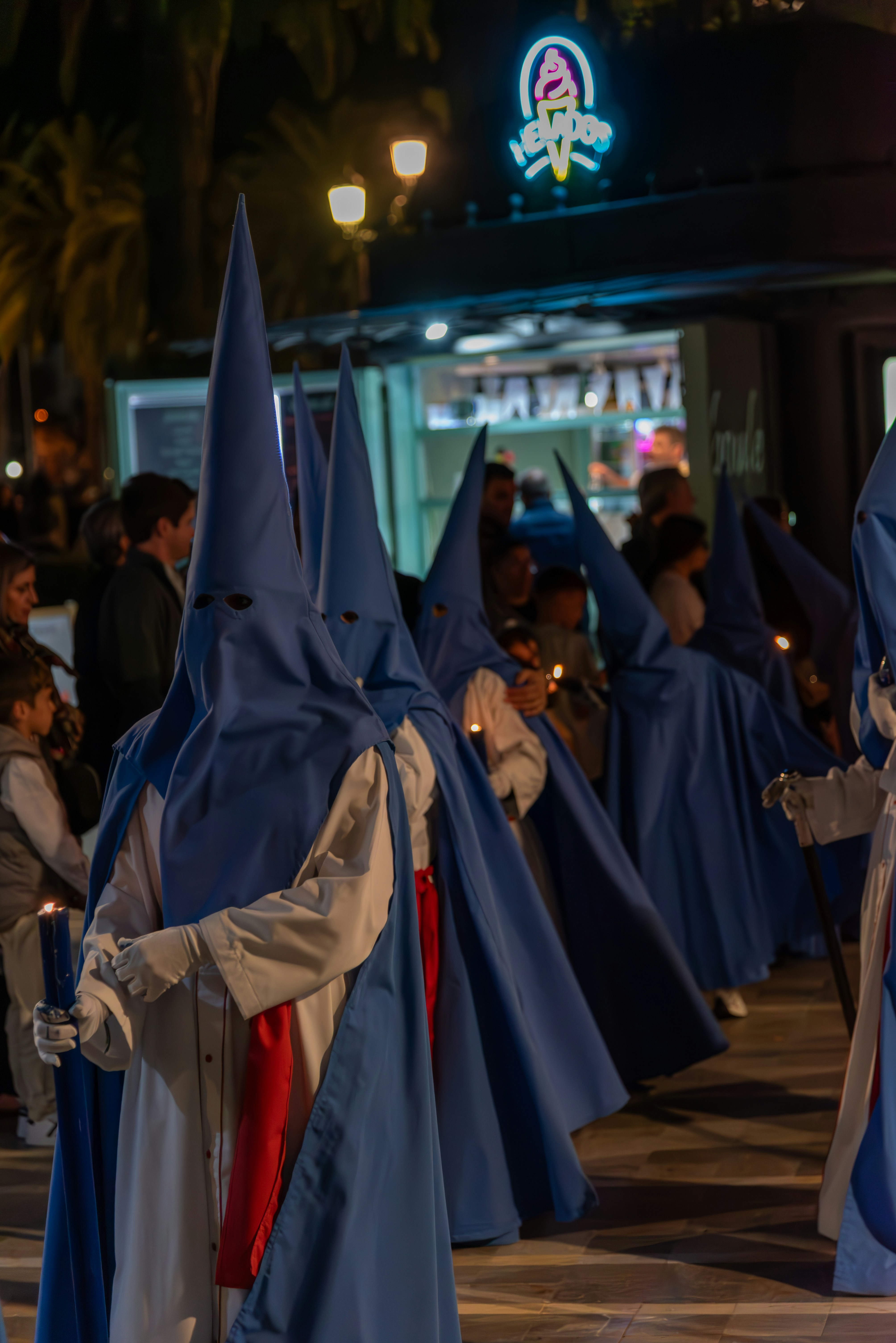 Orang-orang berjubah berkerudung berjalan di malam hari.