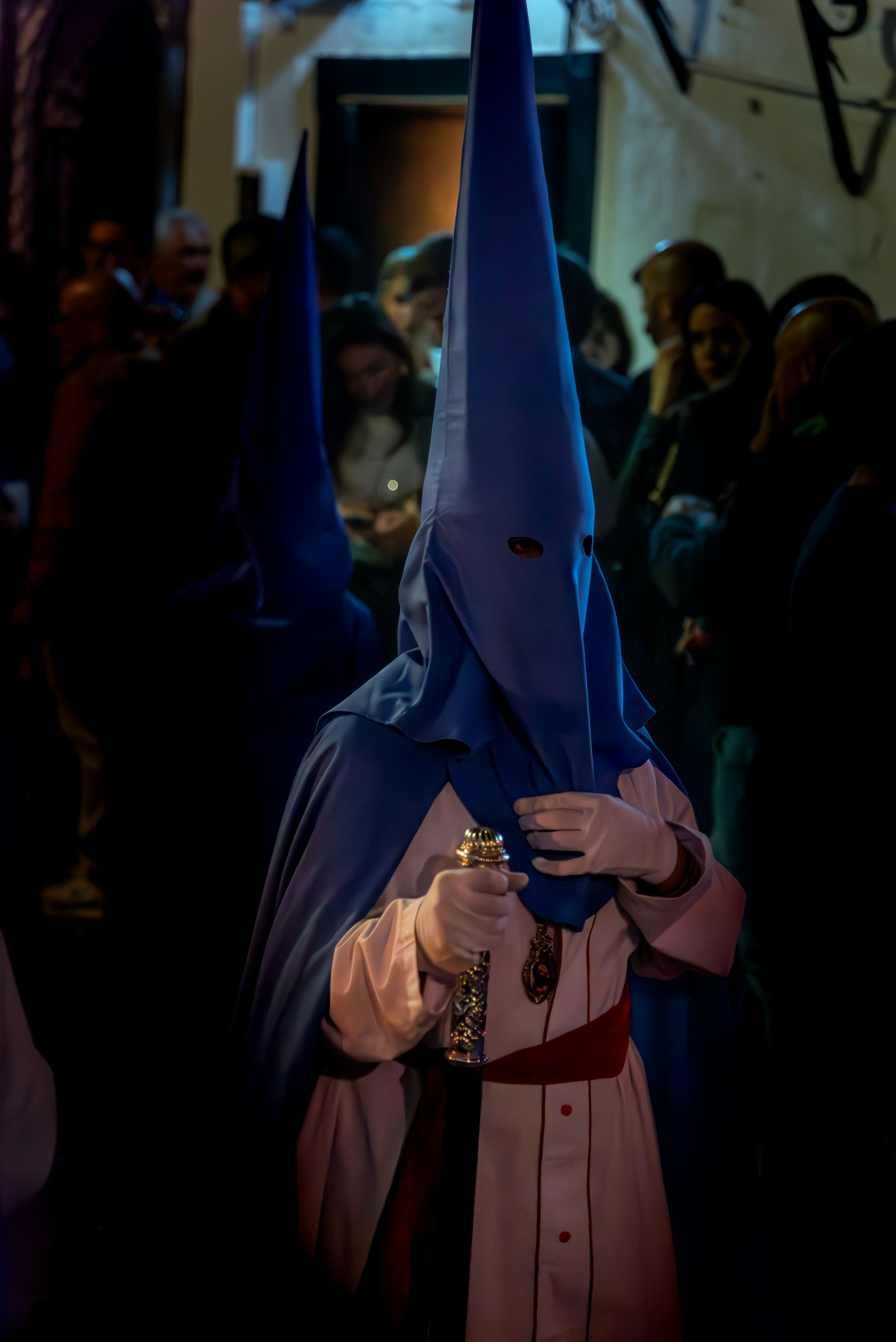 A figure wearing a cowl walks through the night.