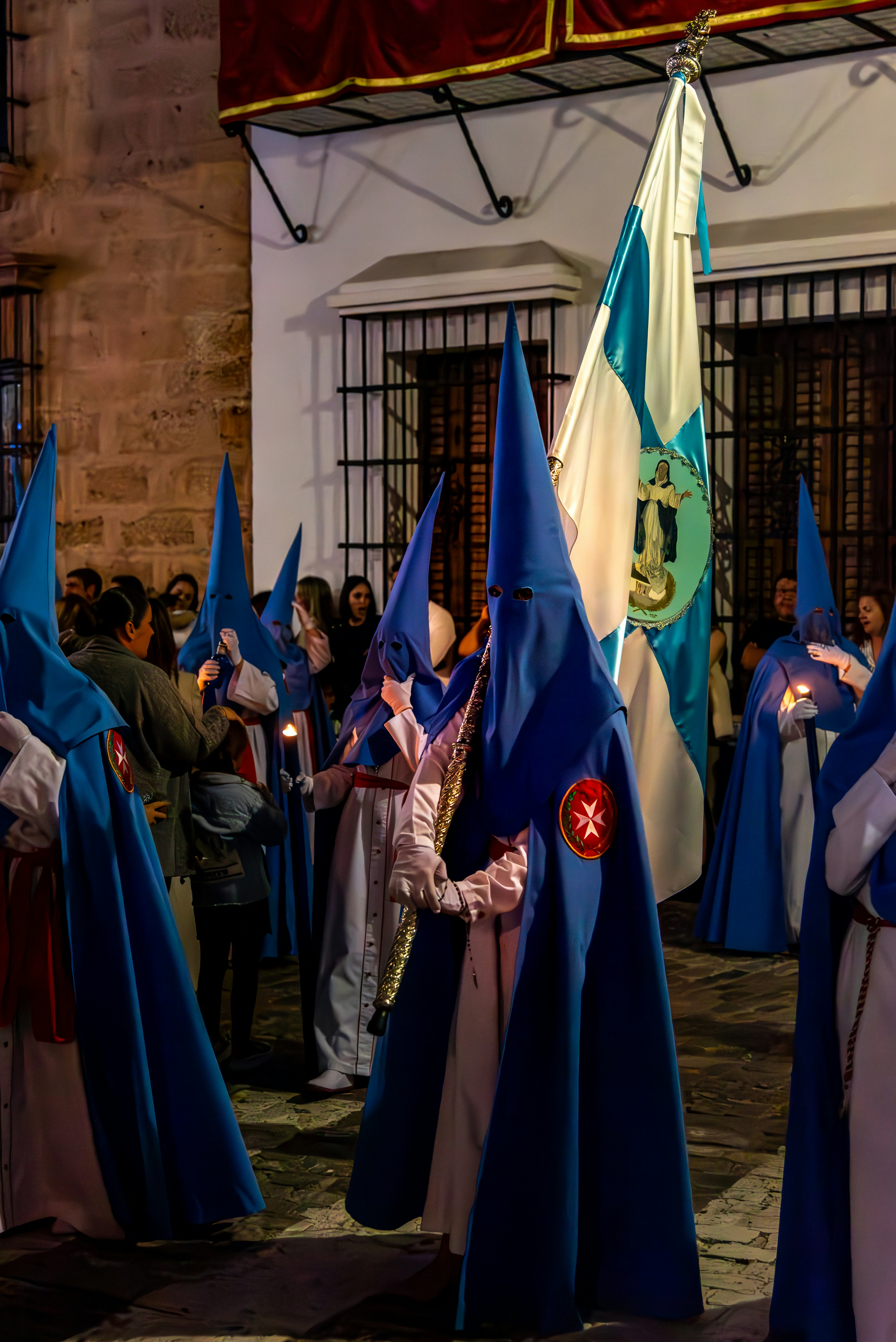 People in blue hooded robes are in a procession.