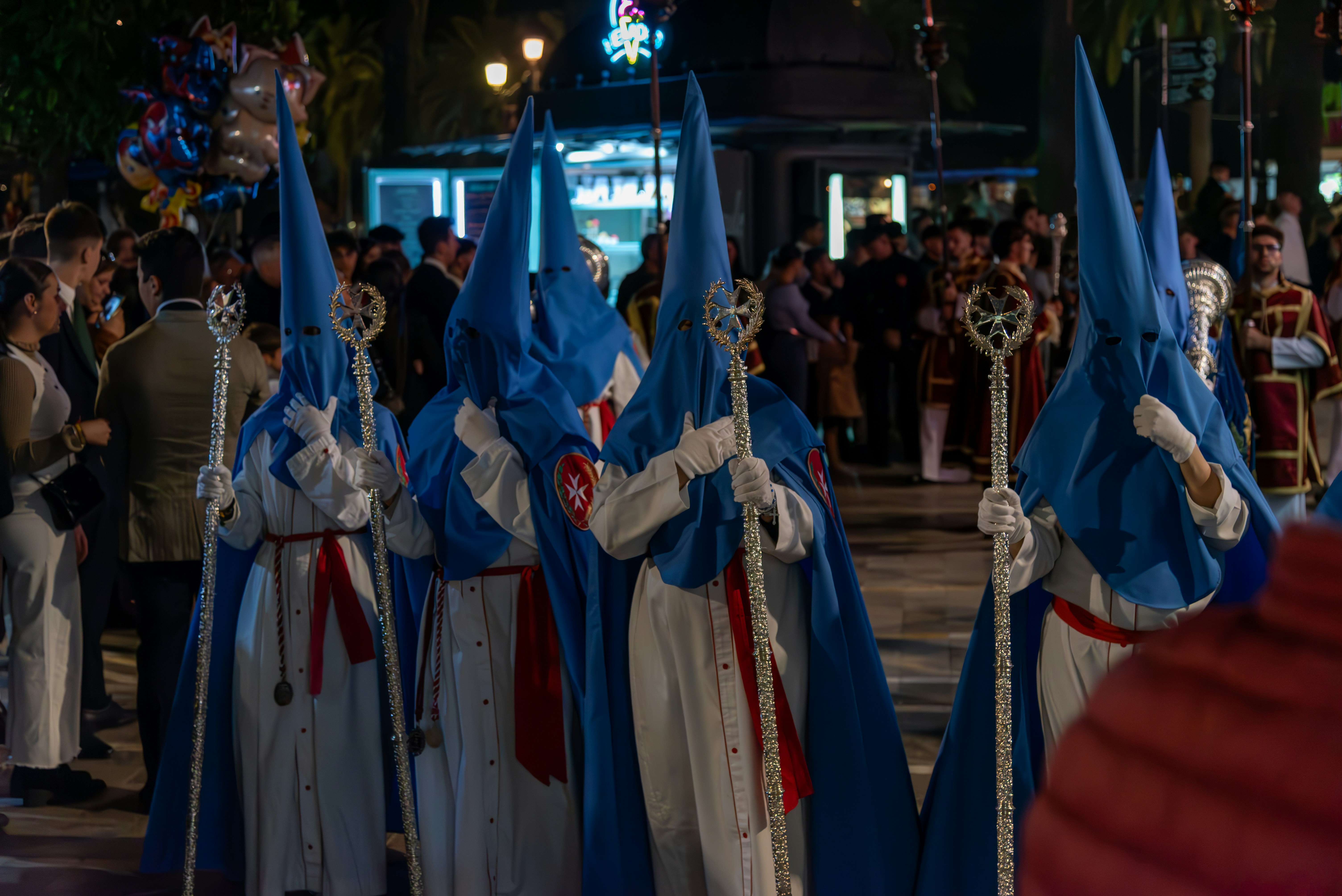 People in hooded robes march in a parade.