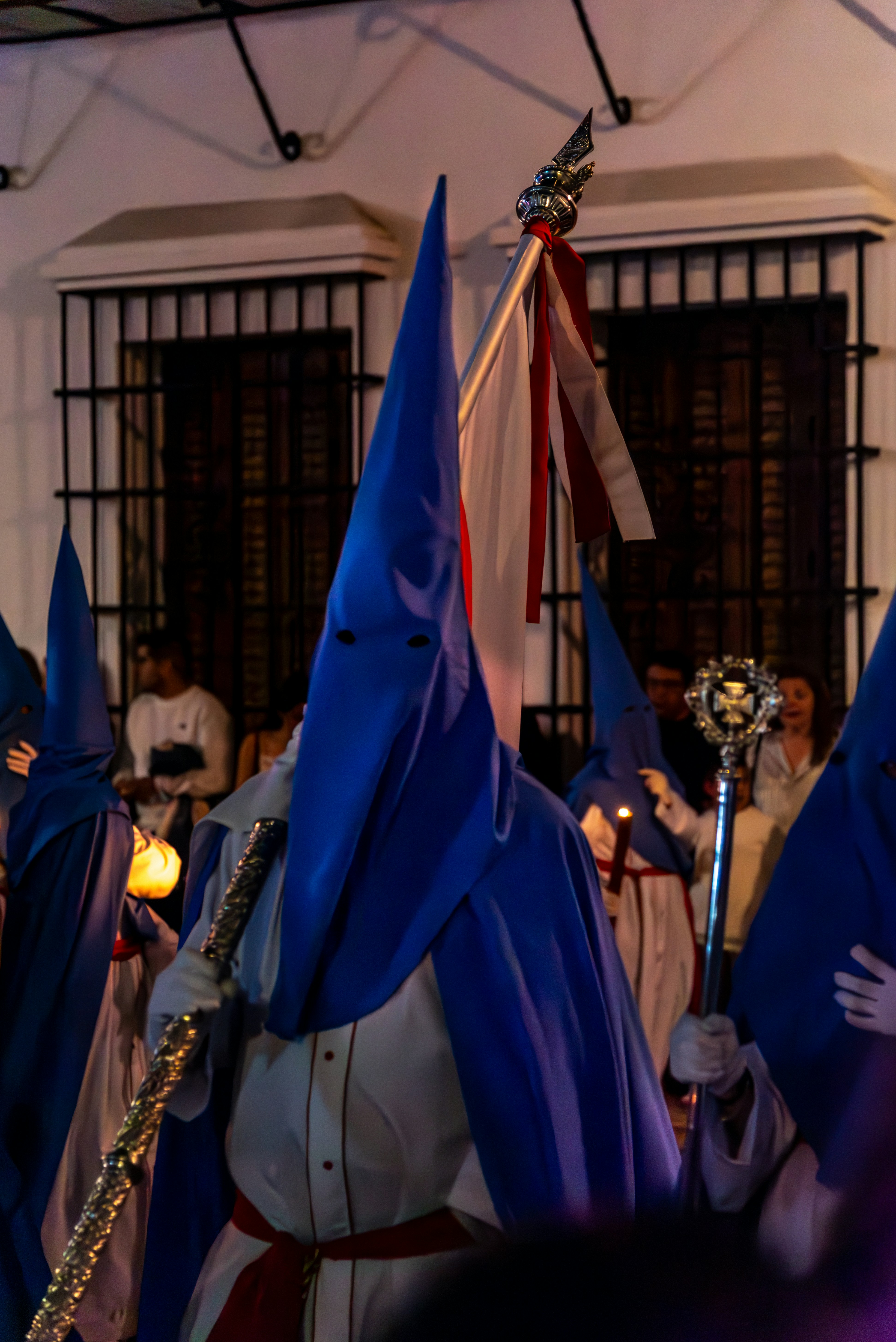 Procession participants wear hoods and hold staffs.