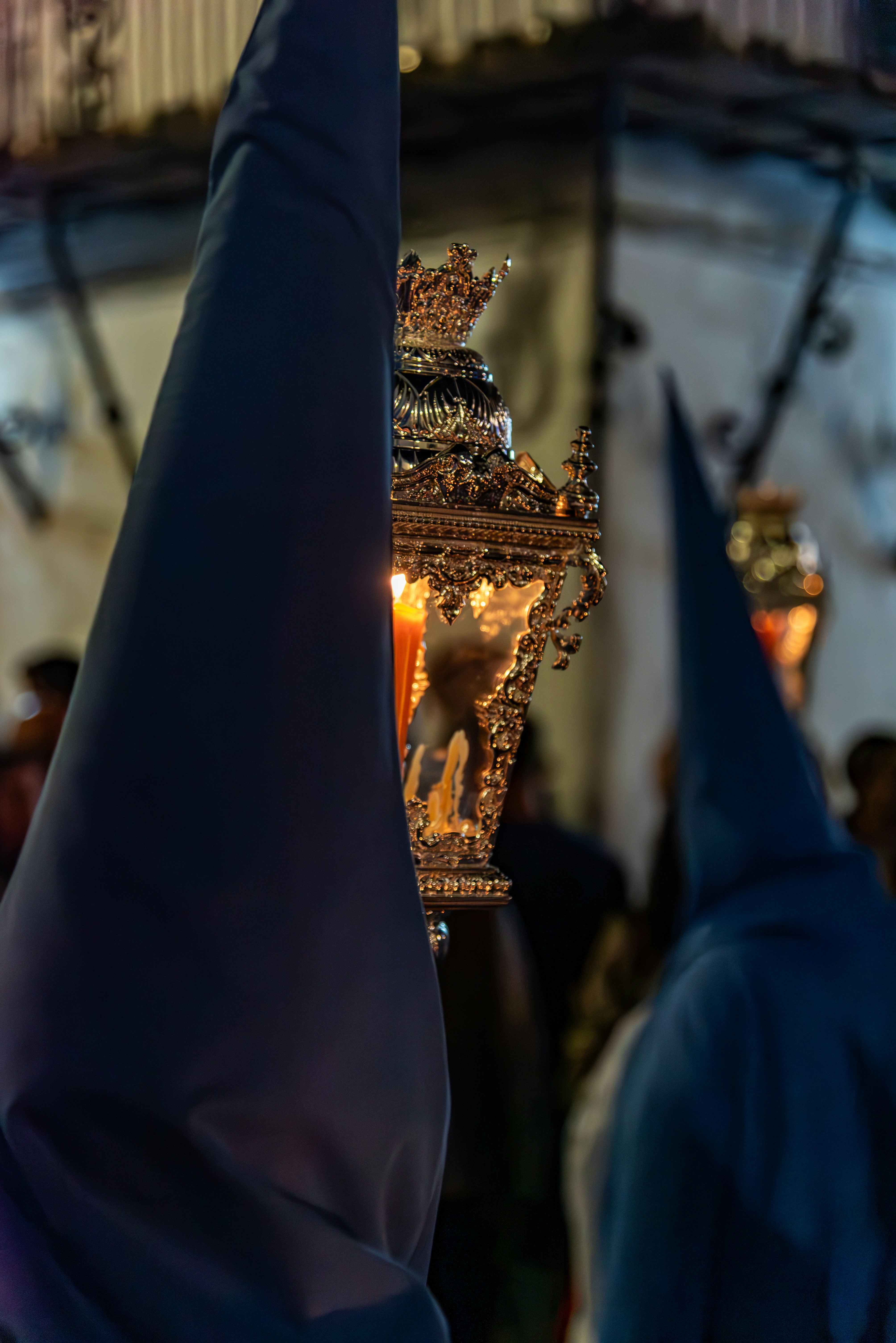 People in hooded robes carry a religious artifact.