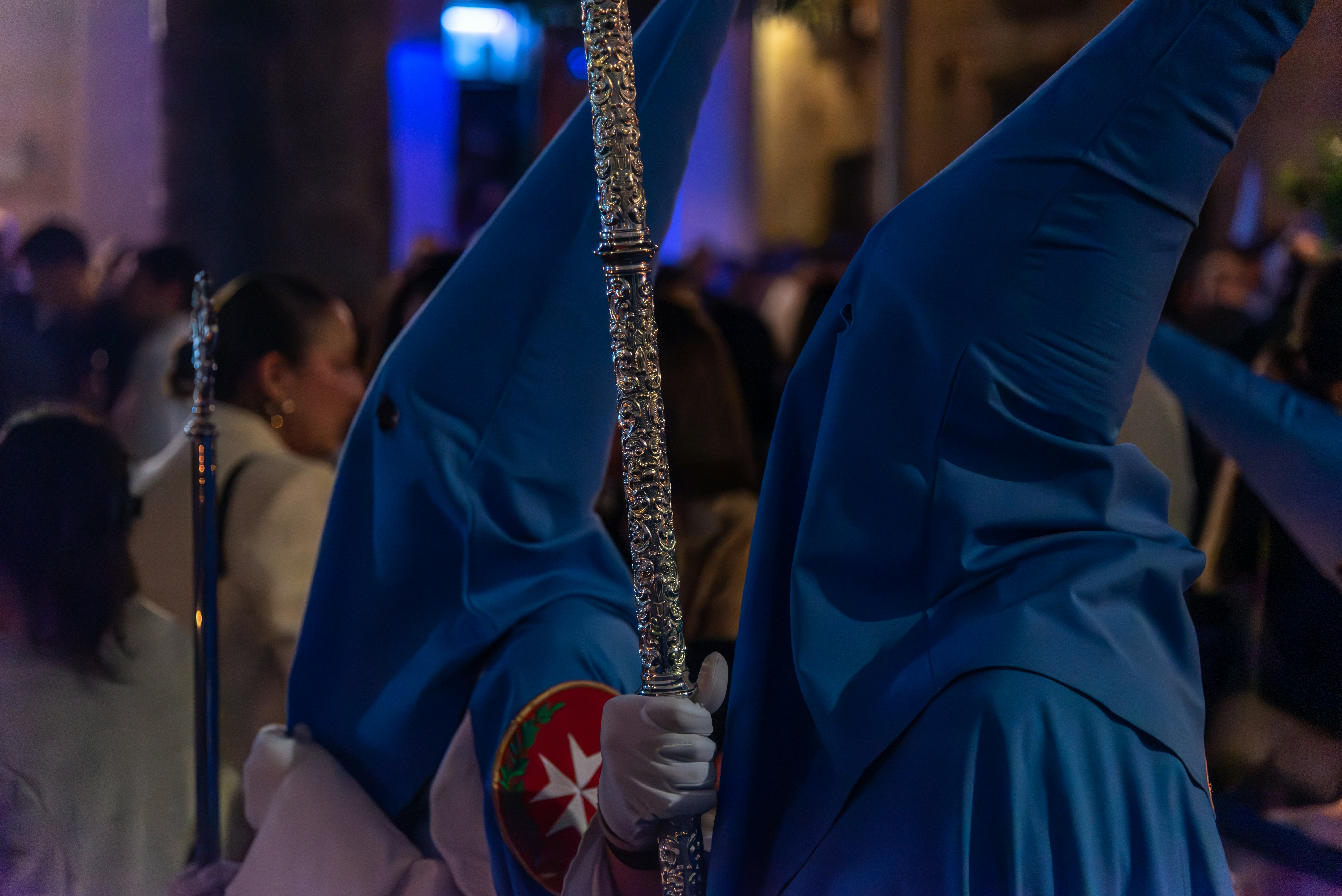 People in blue hoods are holding tall objects.