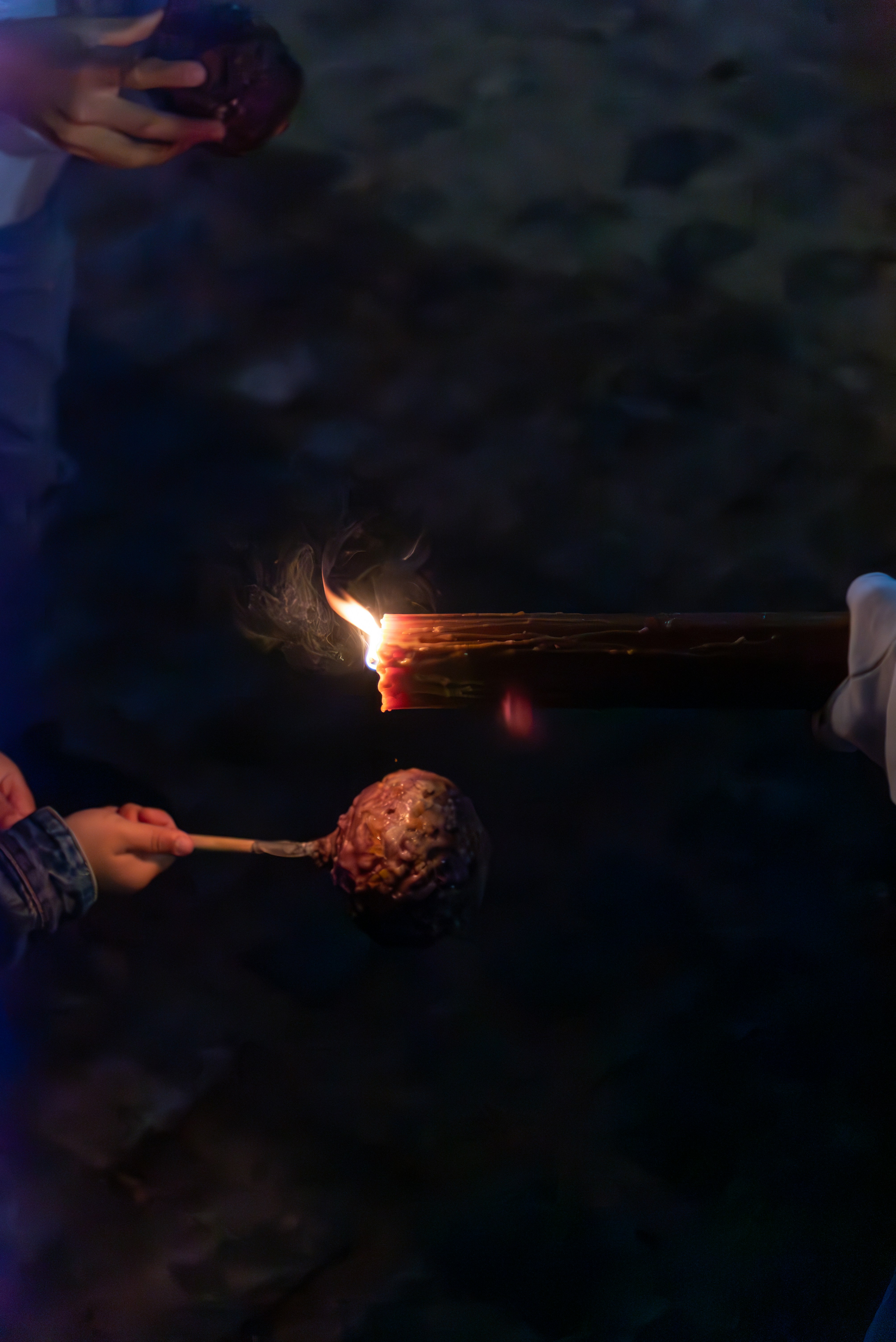 A person lights a torch with a burning log.