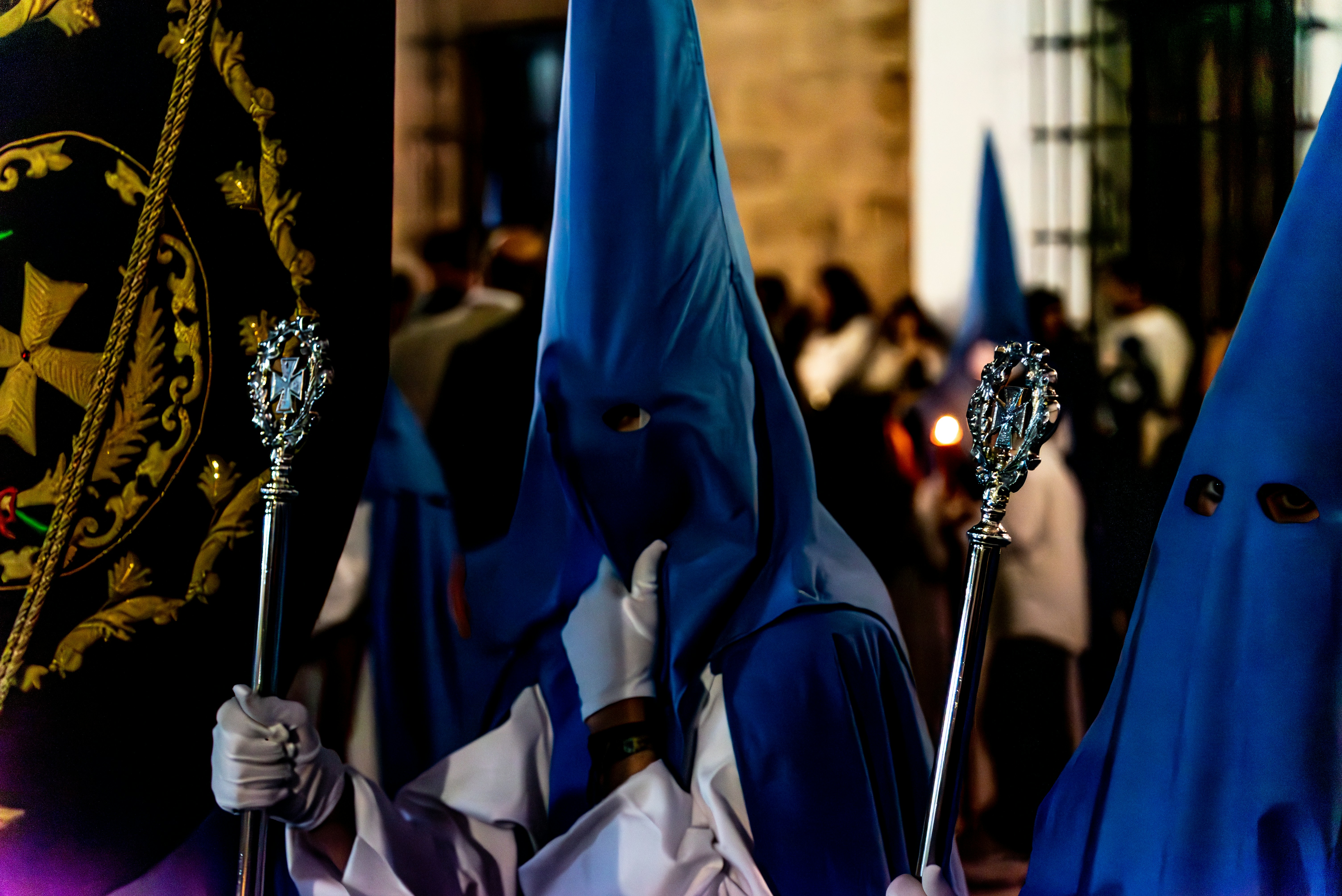 People wearing blue hoods participate in a procession.