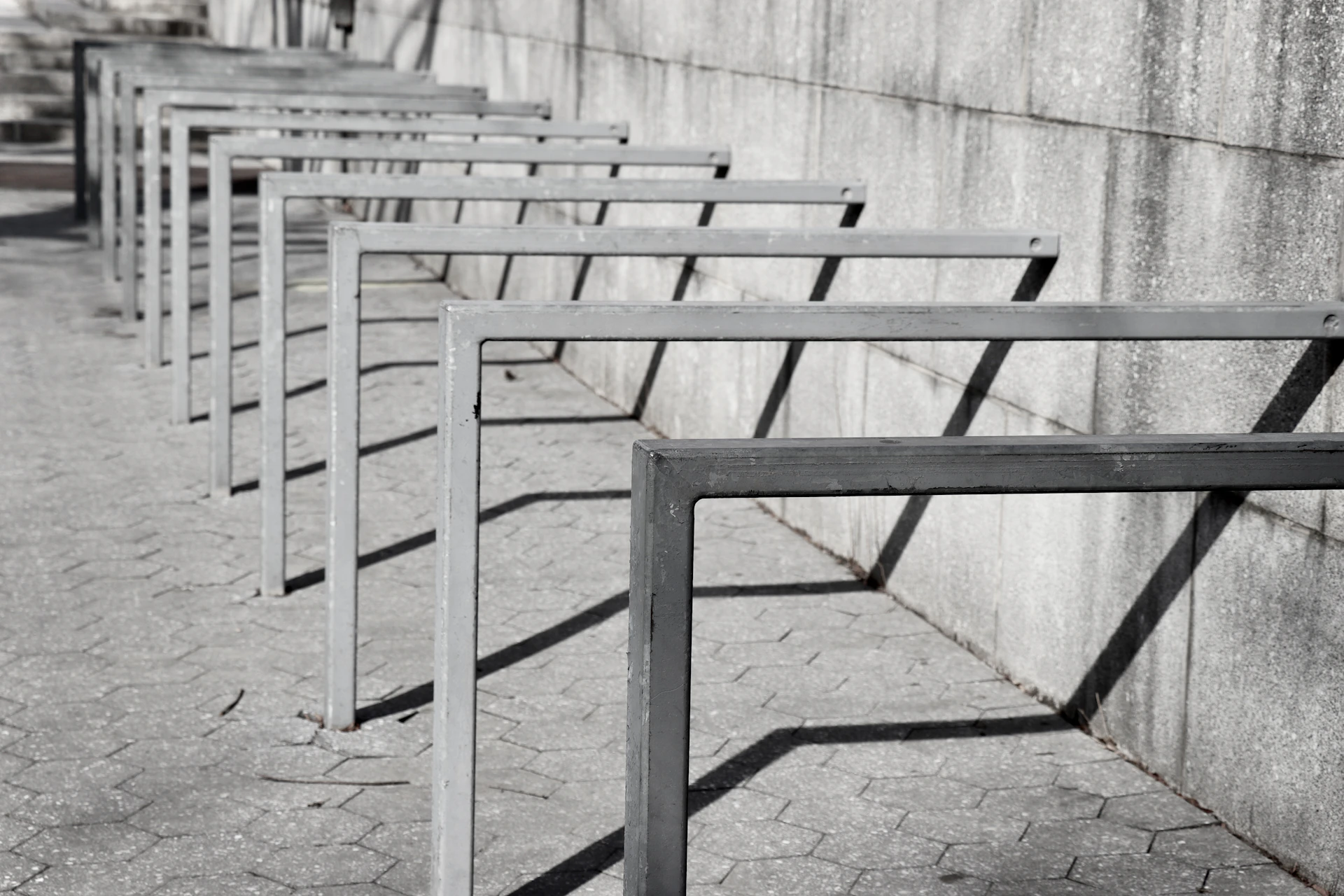 Bike racks cast shadows against a wall.