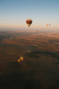 Hot air balloons drift across a vast, golden landscape