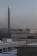 Factory with a tall smokestack on a foggy day.