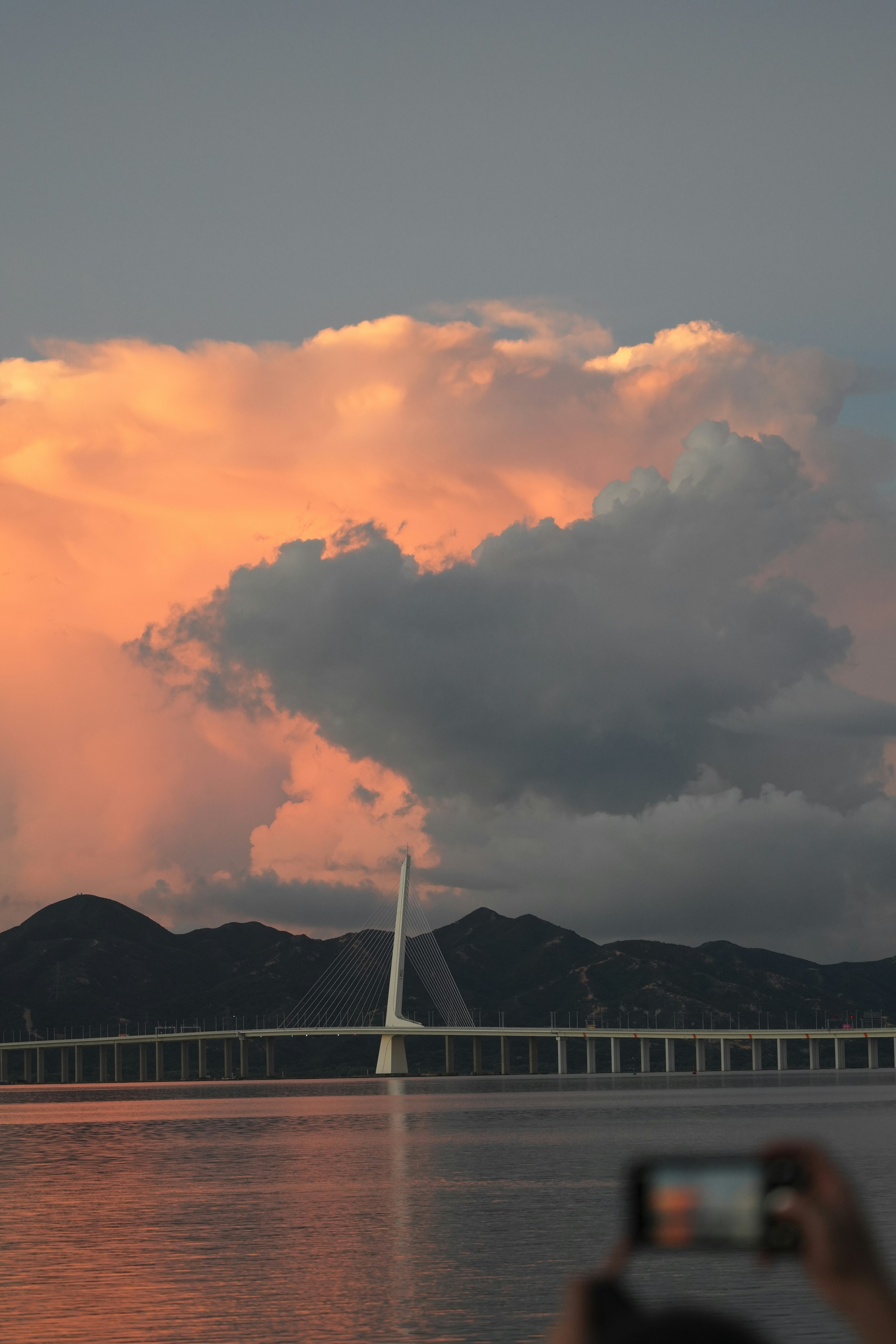 Bridge reflects the sunset’s fiery, dramatic sky.