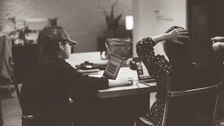 Two people are working at a table in an office.