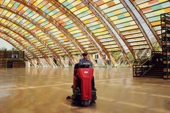 A person uses a floor scrubber inside a building.