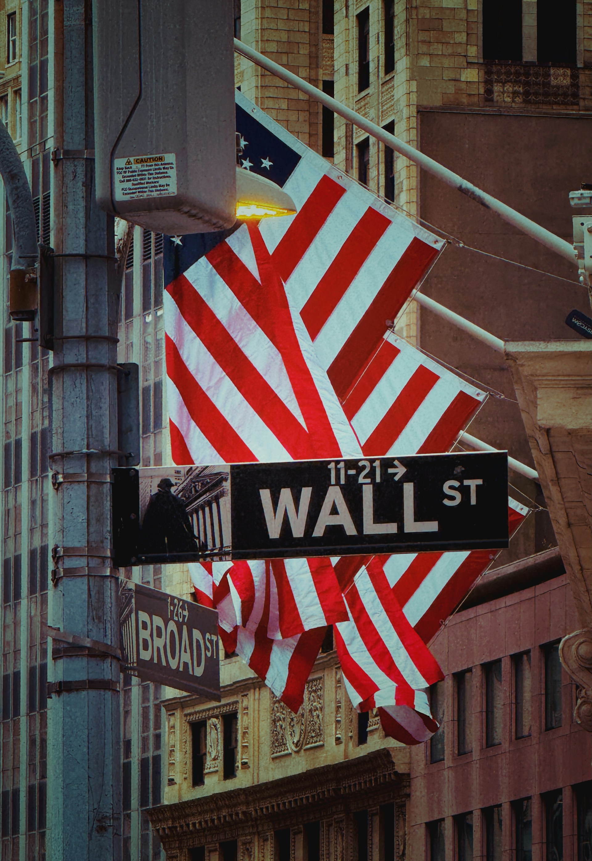 Wall street sign with flags waving.
