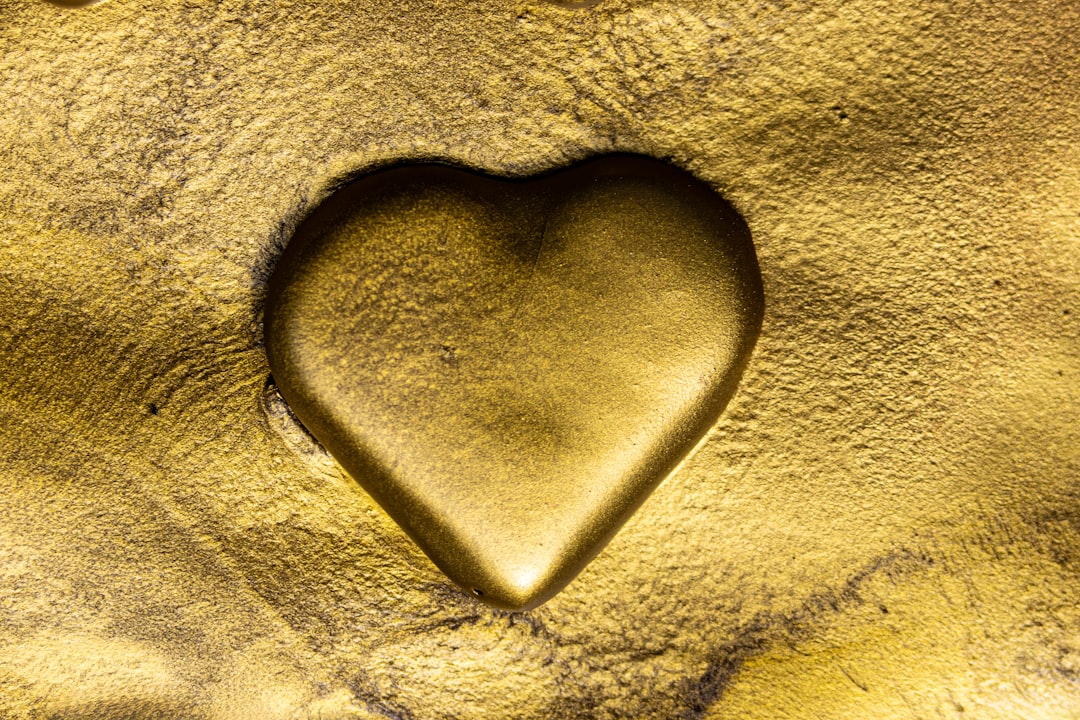 A gold heart is carved into the sand.