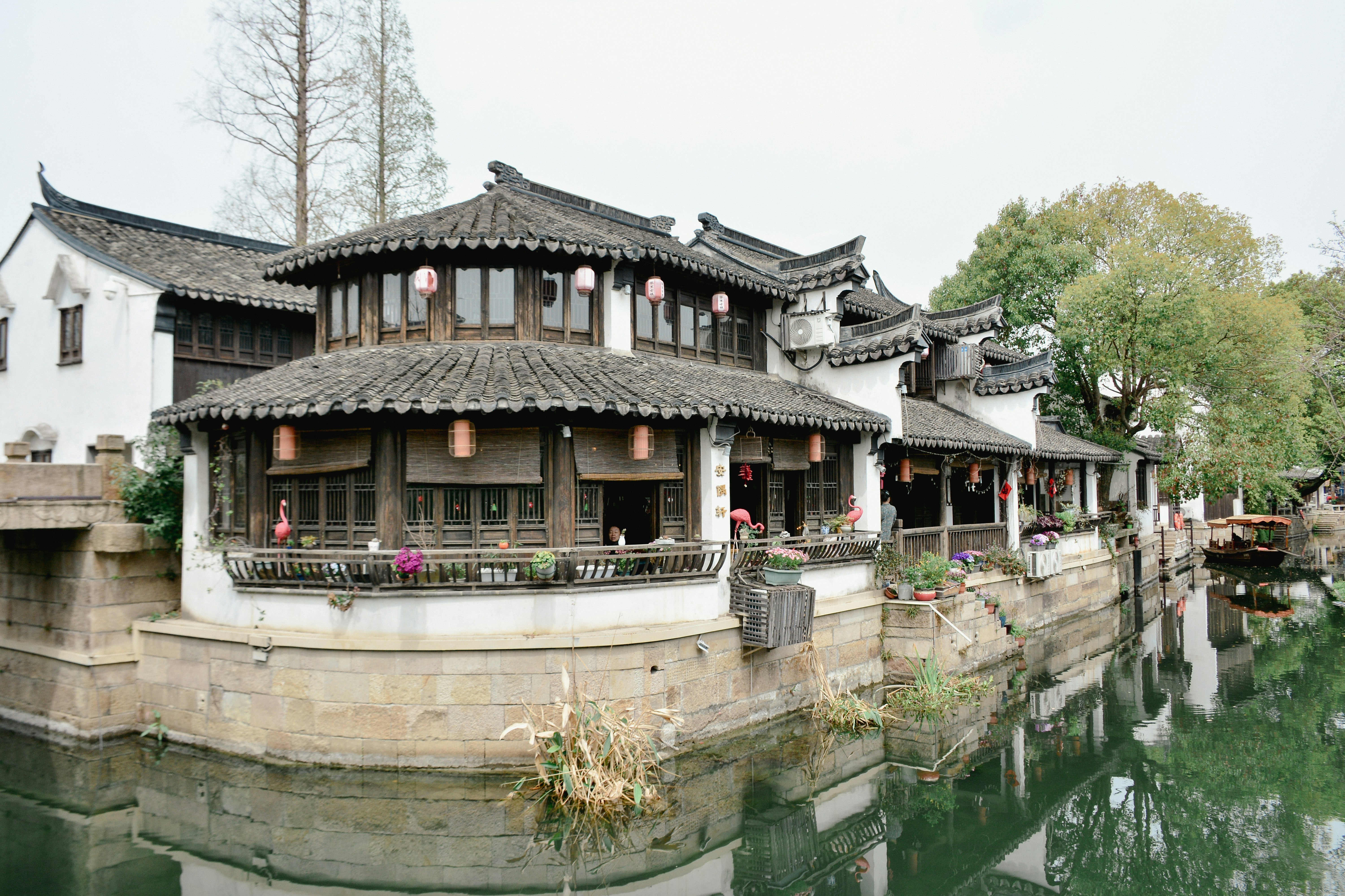 Traditional chinese architecture sits along a waterway.