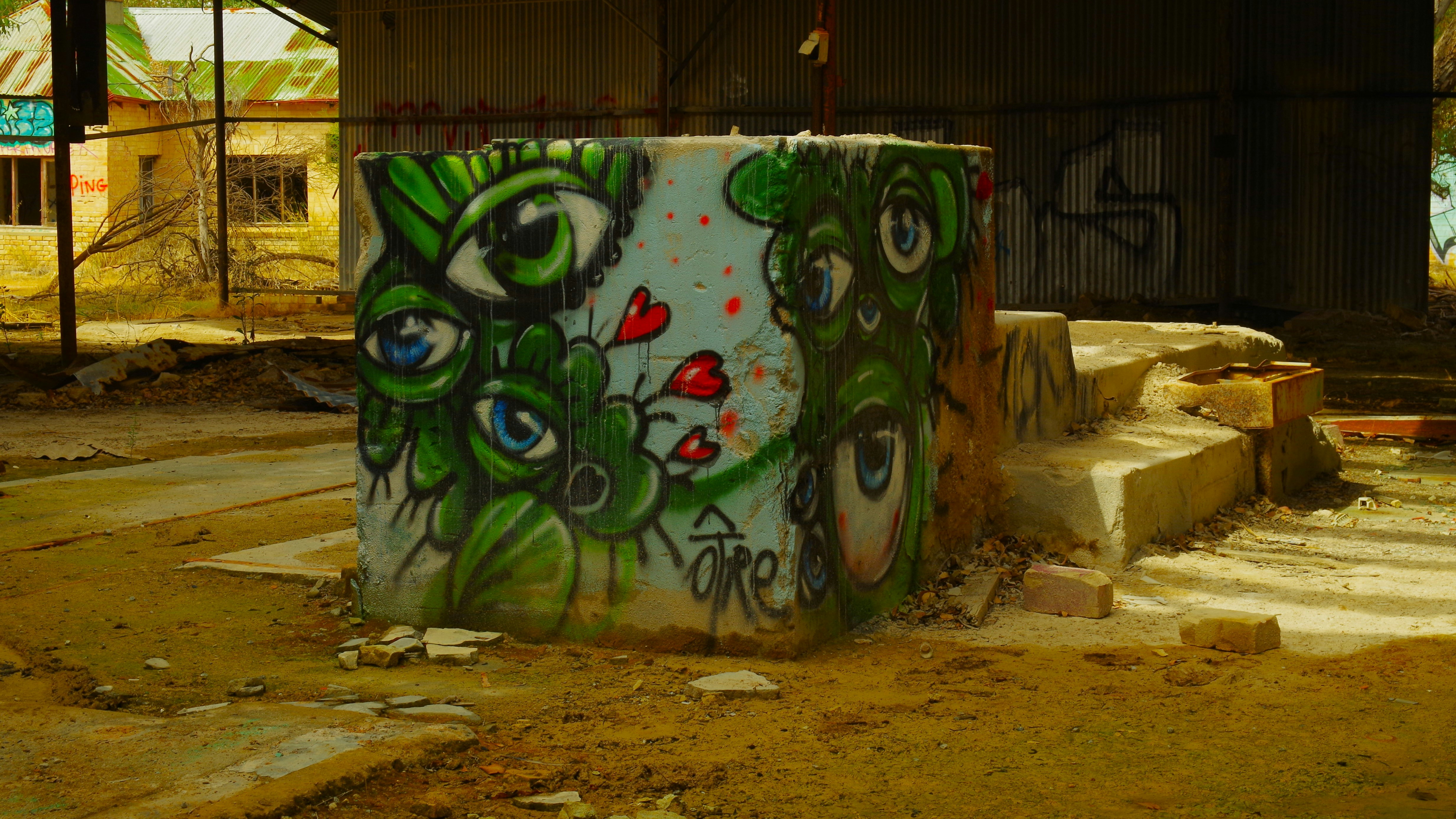 Graffiti of many eyes adorns a concrete cylinder.