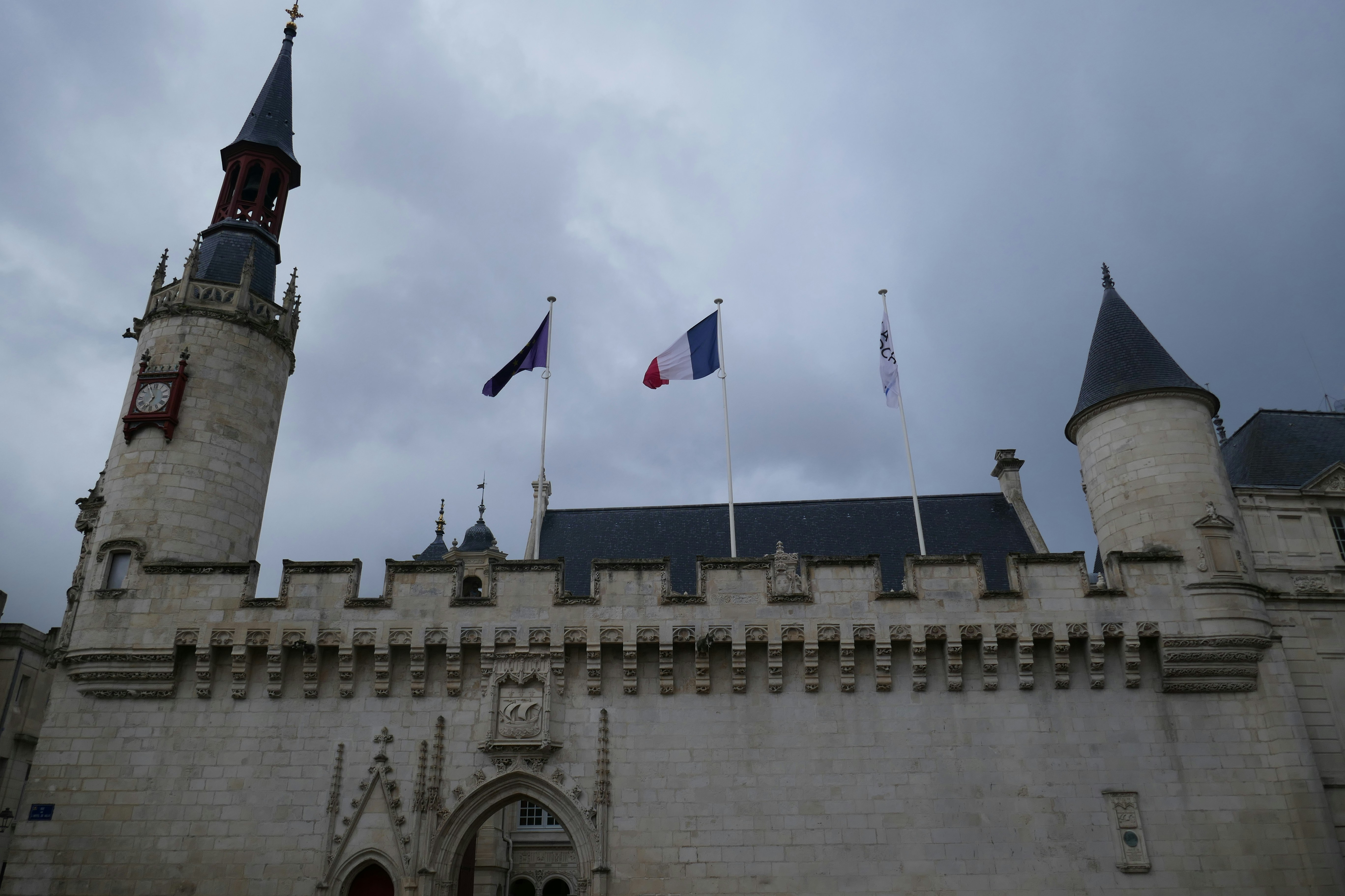 A castle displays flags under a cloudy sky.
