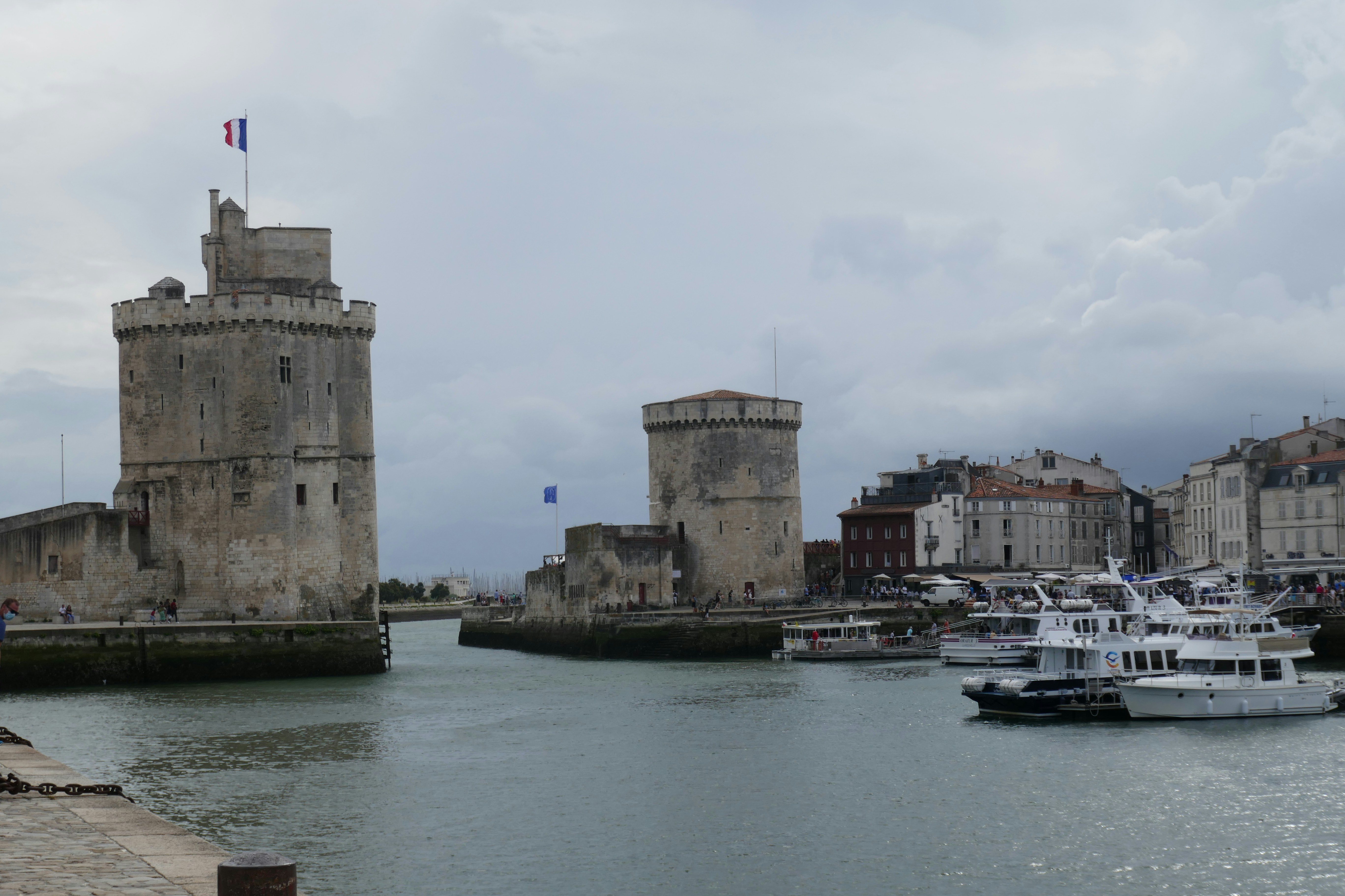Historic towers and boats are in a harbor.