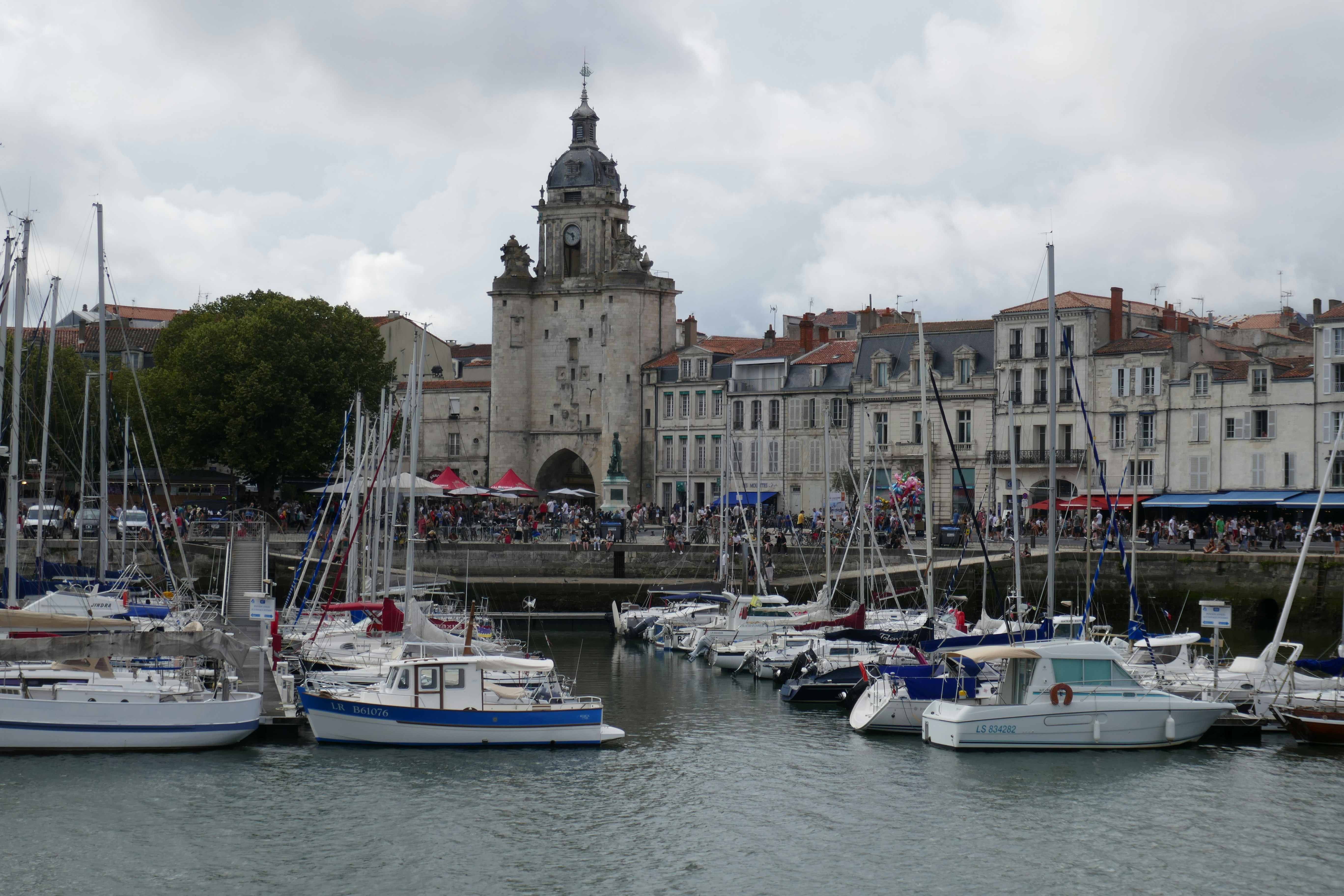 Boats fill a harbor with a stone building.