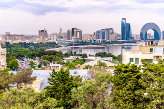 Modern city skyline with trees and water.