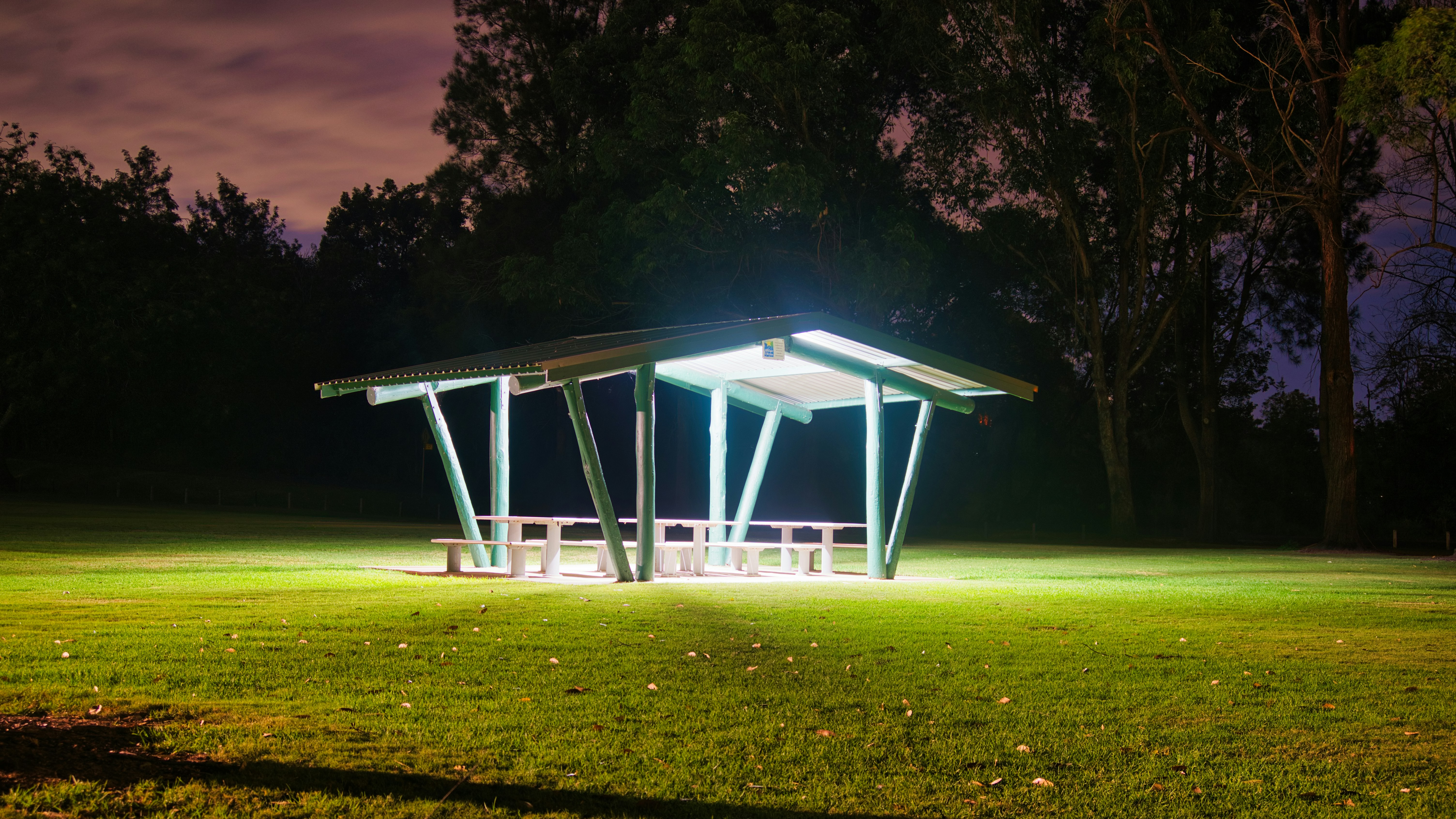 Ein beleuchteter Pavillon bei Nacht in einem Park.