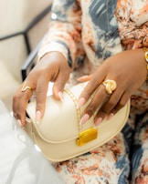 Woman holds a purse and wears rings.