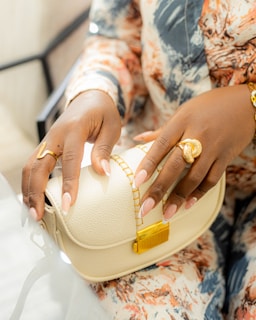Woman holds a purse and wears rings.
