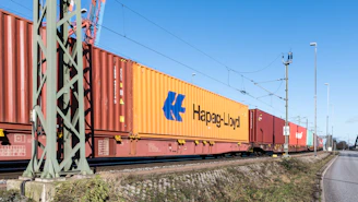 Train hauling shipping containers along the tracks.
