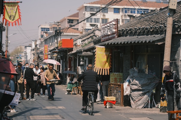 People walk and bike through a bustling street.