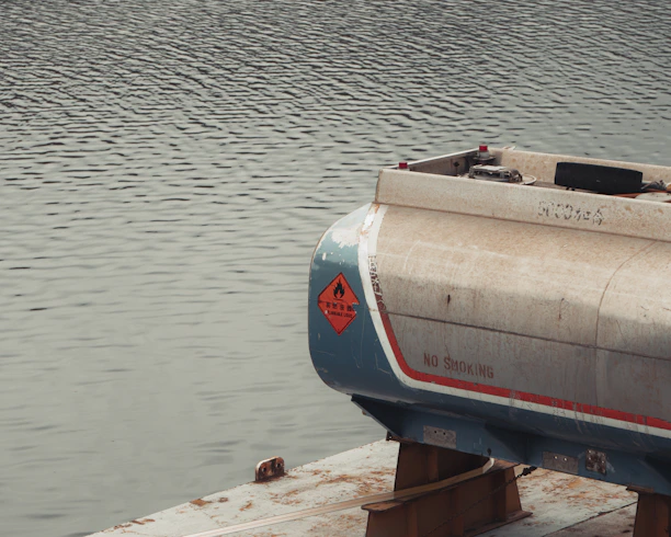 A fuel tank rests on a platform over water.